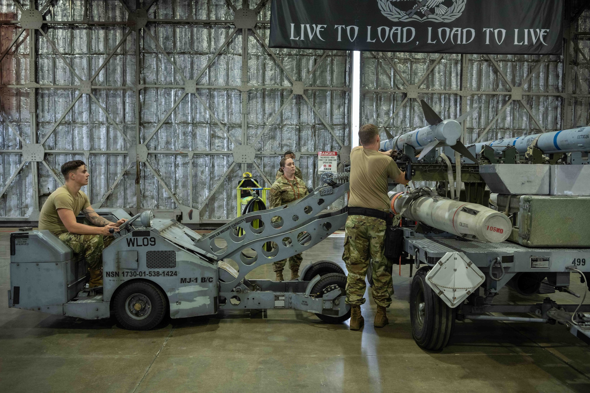 U.S. Air Force Airmen assigned to the 13th Aircraft Maintenance Unit secure an AIM-9X Sidewinder to an MJ-1 standard lift truck, before loading it onto an F-16 Fighting Falcon during the second quarter load crew competition at Misawa Air Base, Japan, July 1, 2022.