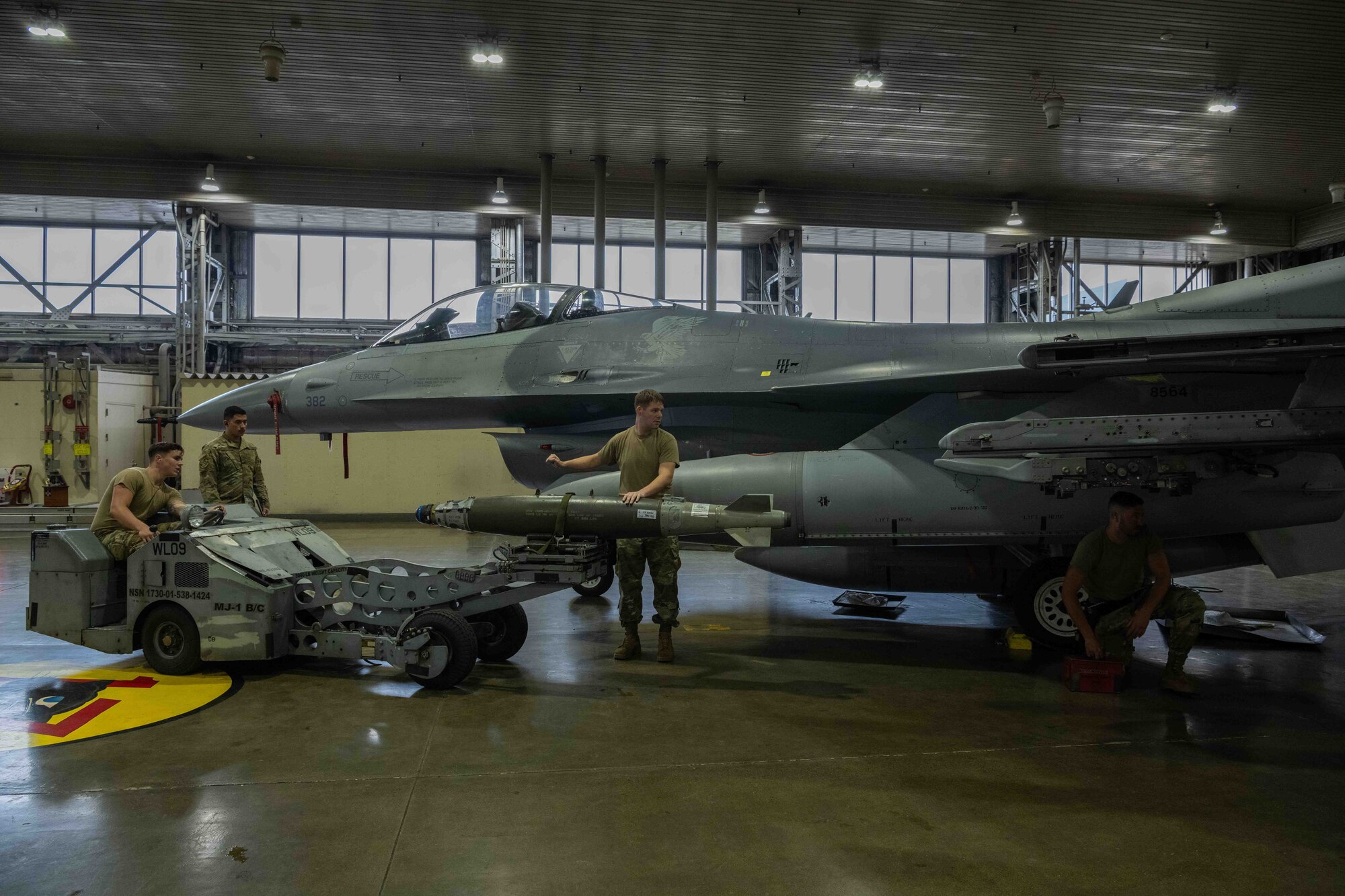 U.S. Air Force Airmen assigned to the 13th Aircraft Maintenance Unit prepare to load a training GBU-31 guided bomb onto an F-16 Fighting Falcon during the second quarter load crew competition at Misawa Air Base, Japan, July 1, 2022.