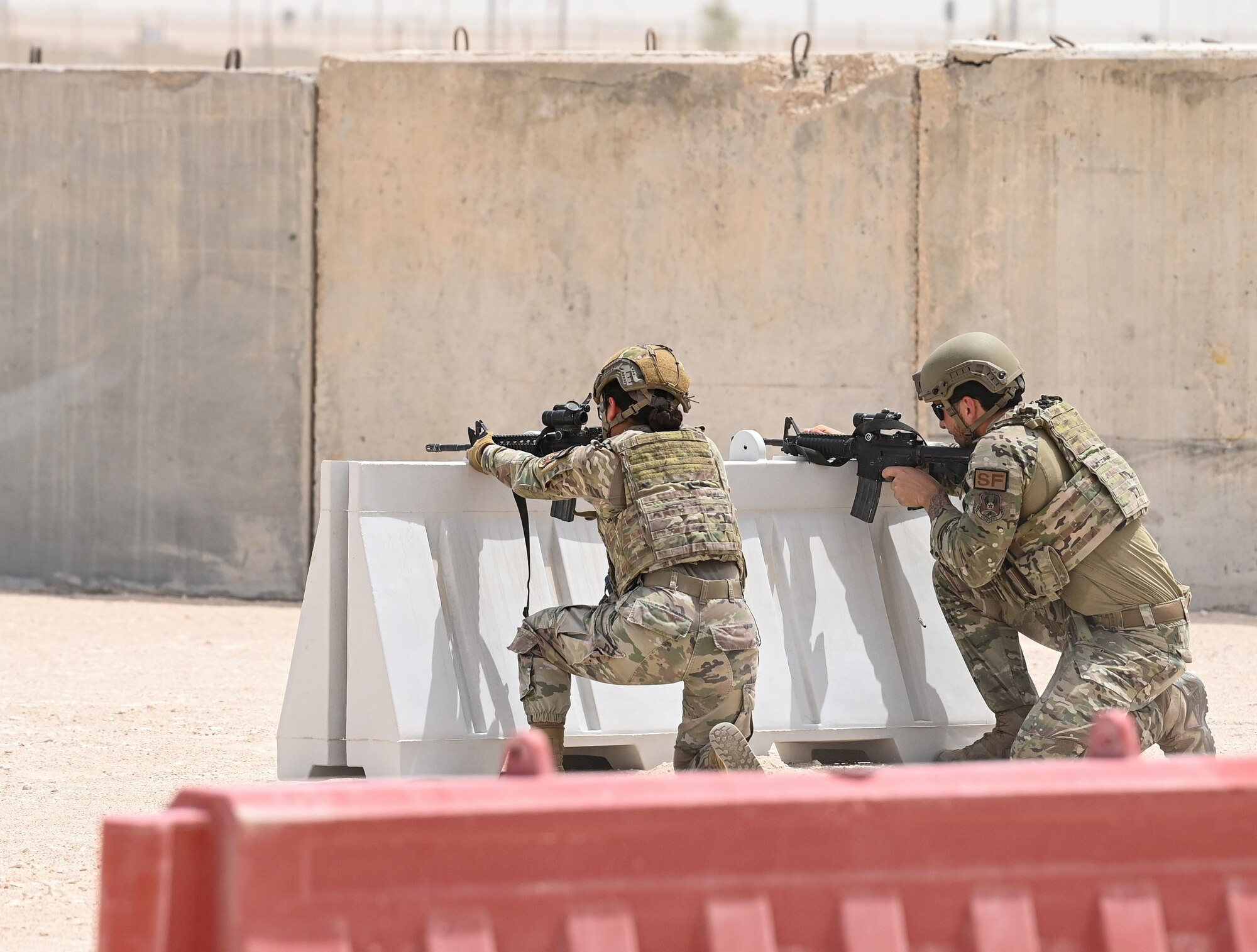 A pair of 379th Expeditionary Security Forces Squadron defenders lay down fire from behind a barricade during a shoot, move and communicate demonstration July 1, 2022 at Al Udeid Air Base, Qatar. The Defenders along with other 379th EMSG airmen showcased how to advance on a target while maintaining fire and communication. (U.S. Air National Guard photo by Tech. Sgt. Michael J. Kelly)