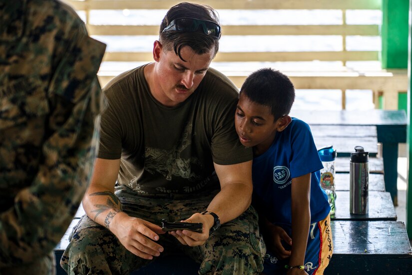 A sailor shows a device to a small boy.