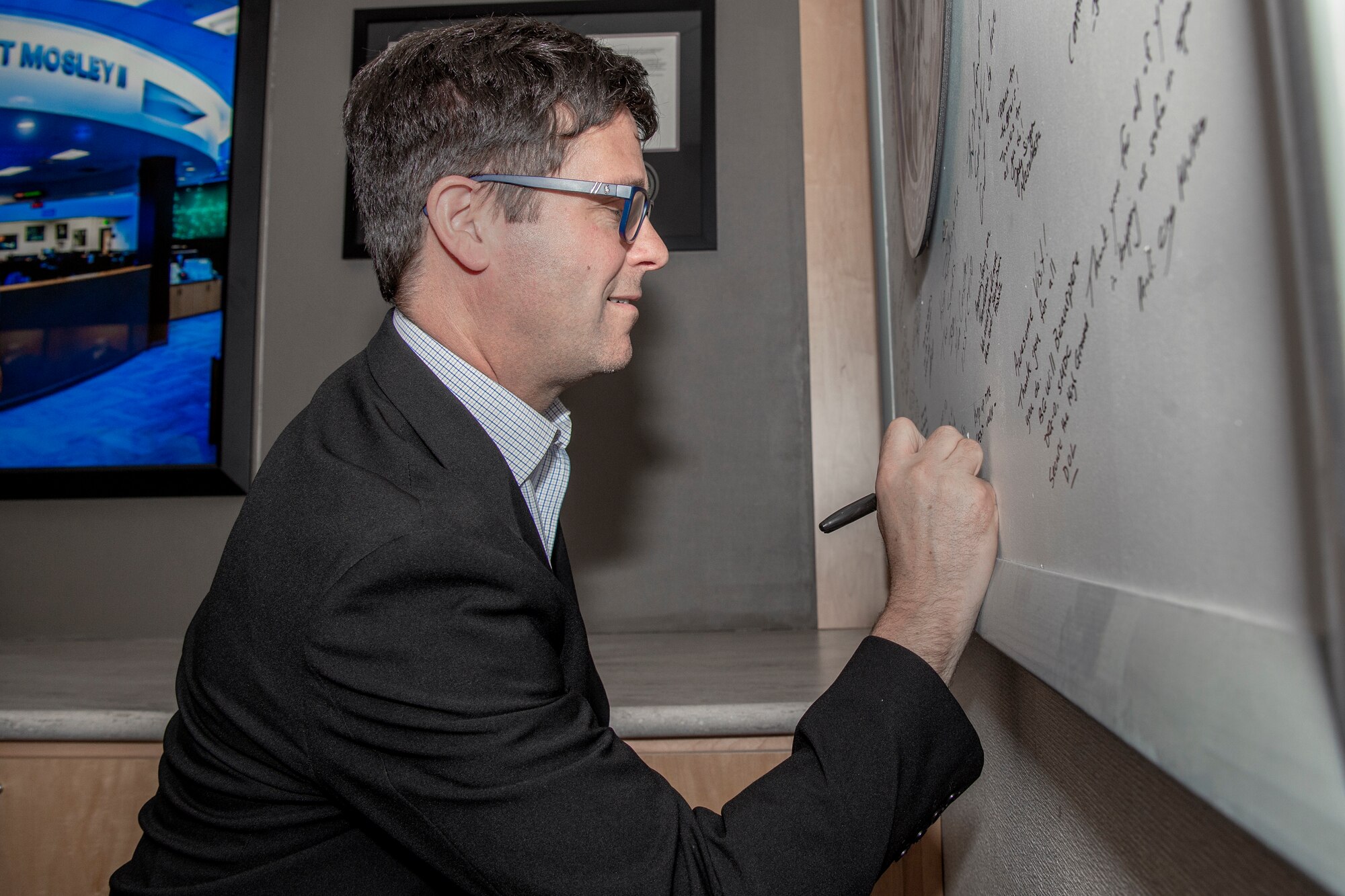 man in suit signing board with marker