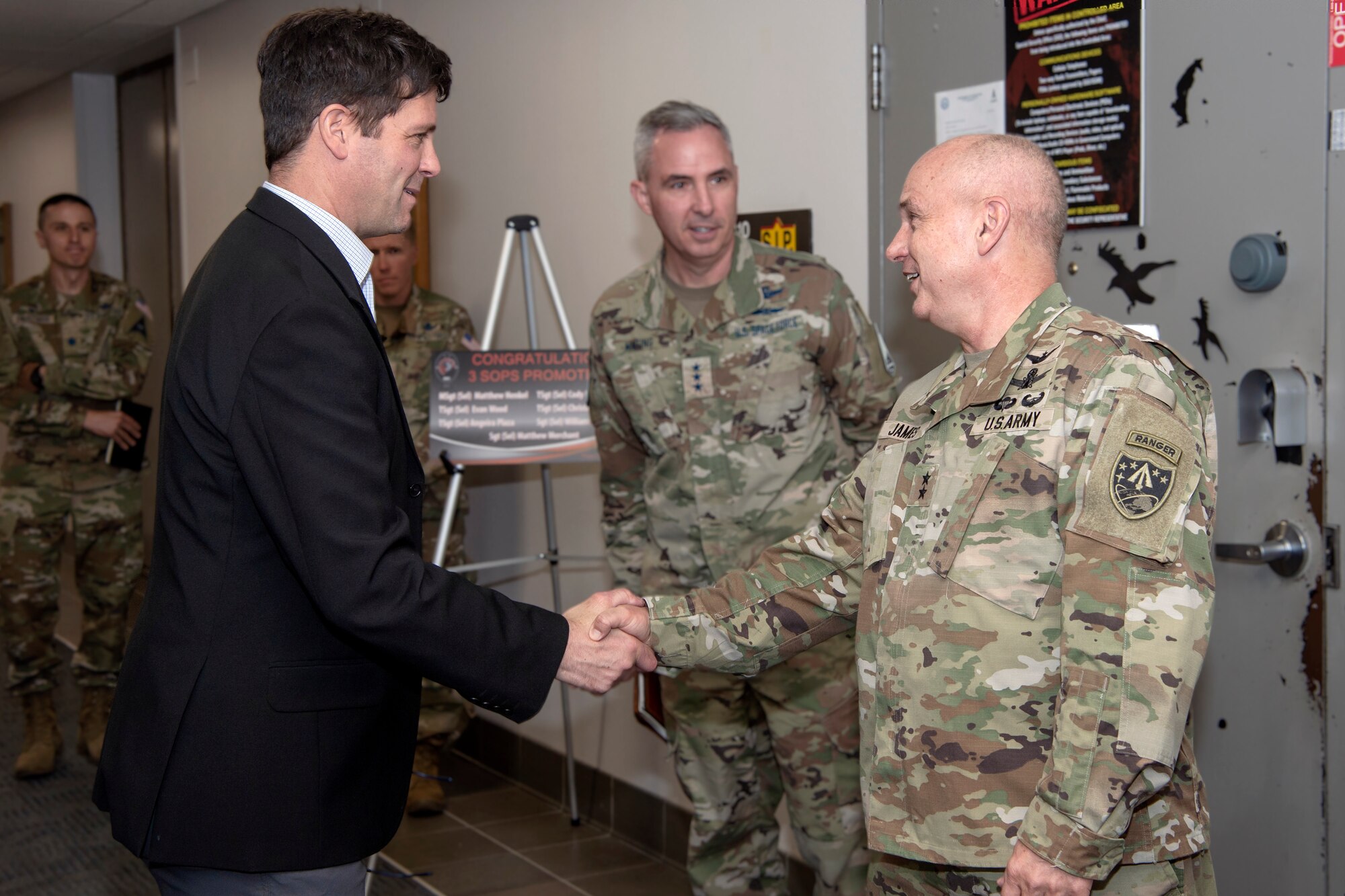 man in suit shaking hands with man in military uniform