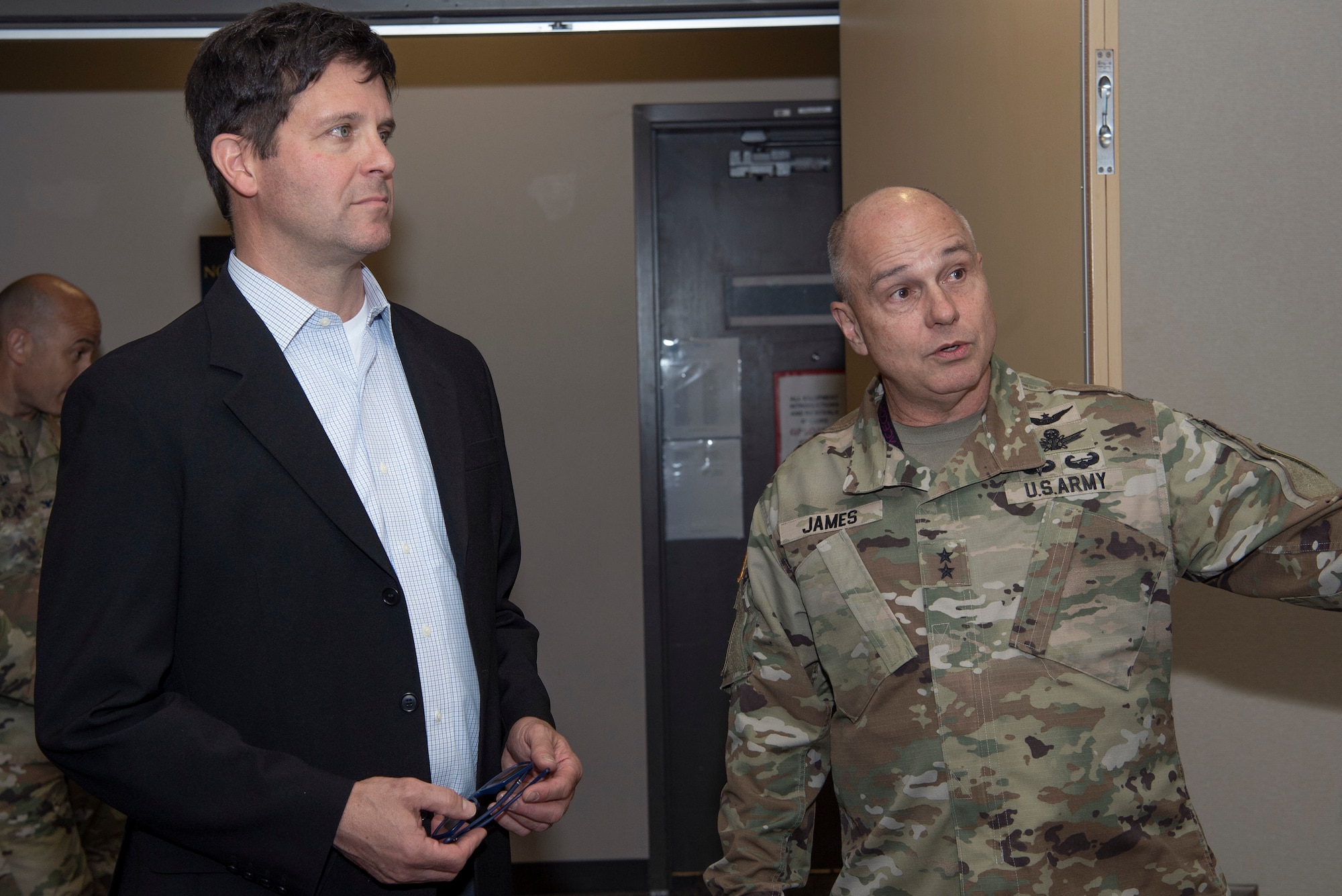 one man in suit standing next to one man in military uniform