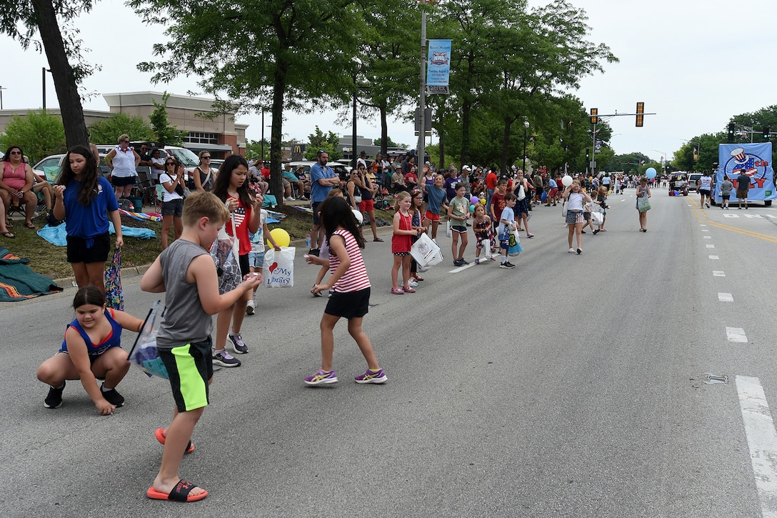 Children stand along the street to receive candy from parade participants from the Rolling Meadows Independence Day parade, July 4, 2022.