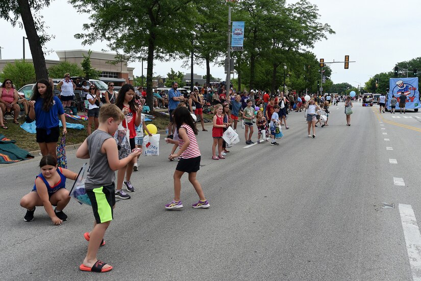 Children stand along the street to receive candy from parade participants from the Rolling Meadows Independence Day parade, July 4, 2022.