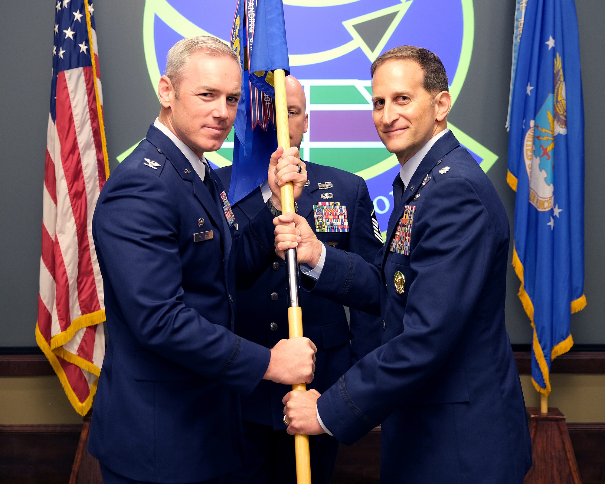 Photo of U.S. Airmen holding unit guidon flag with Airman standing in the background