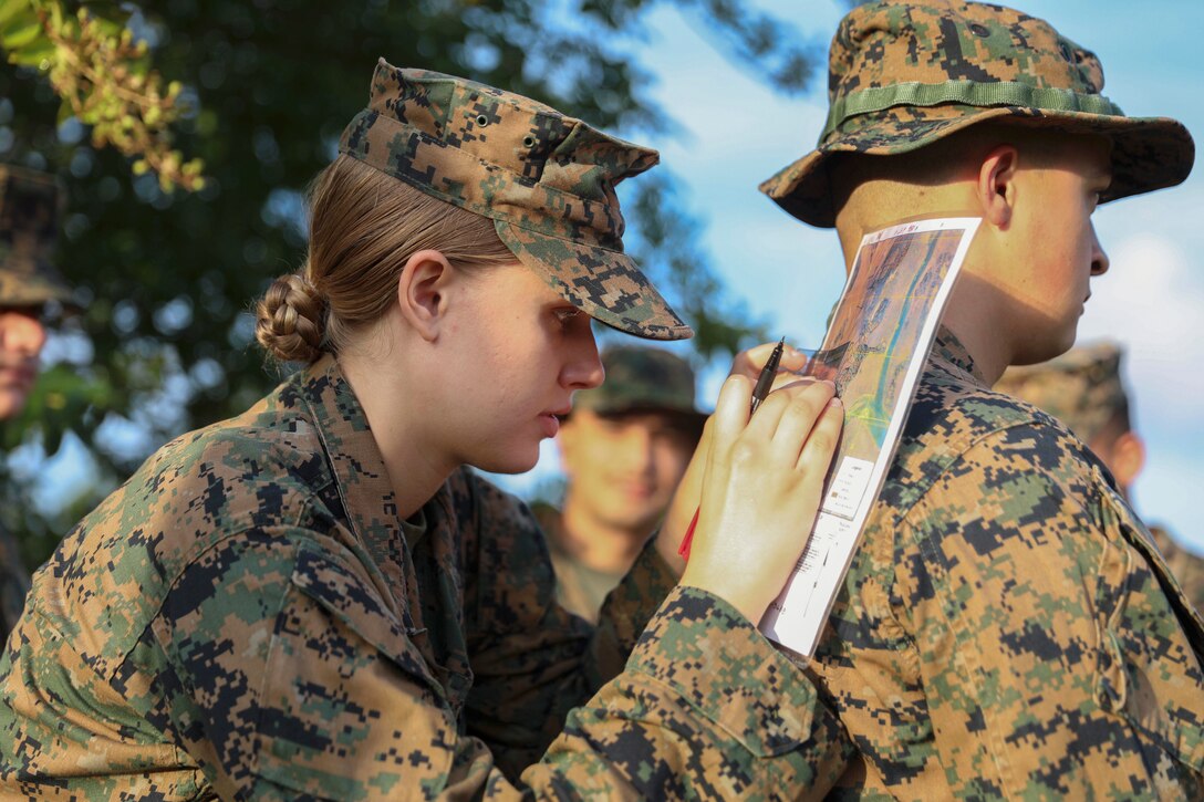 A Marine writes on a piece of paper balanced on the back of a fellow Marine.