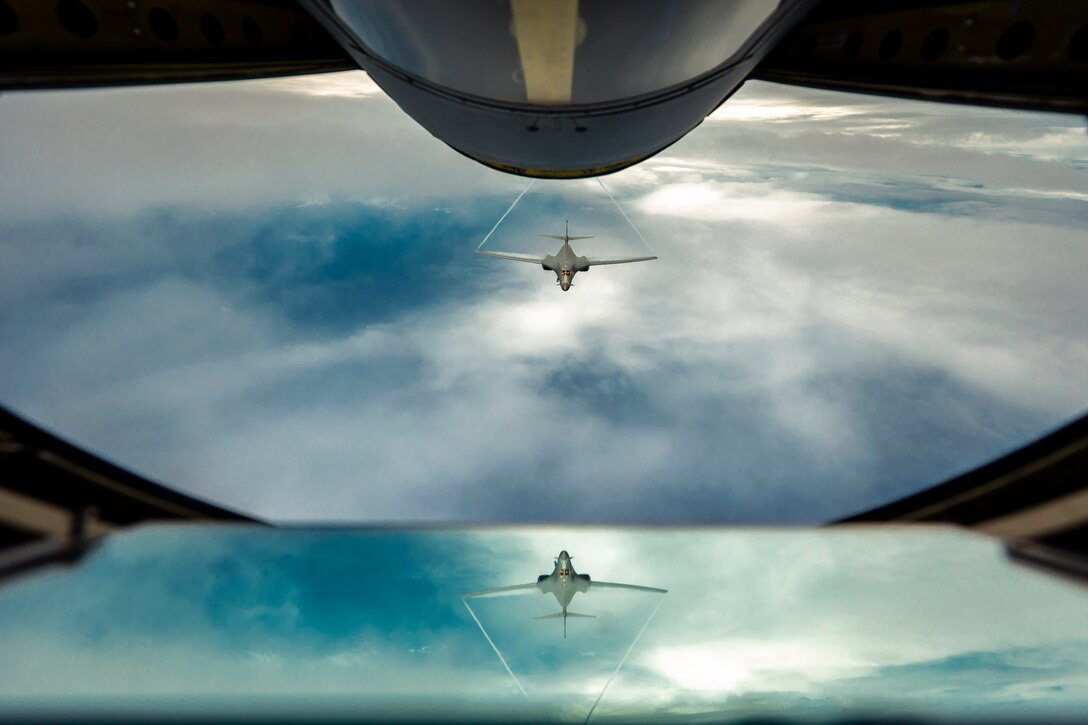 An aircraft flies behind another aircraft over a body of water.