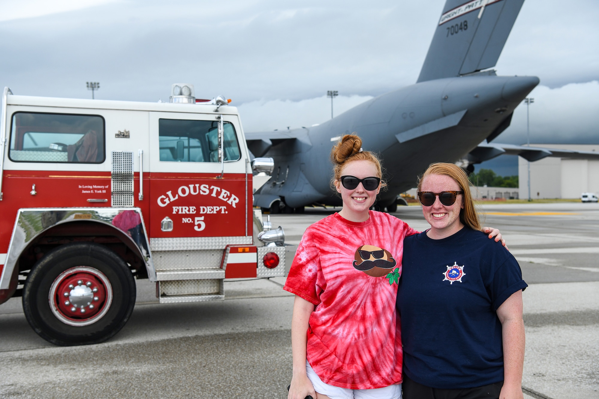 Holly Monast (right) and her sister, Hannah York, pose in front of a fire truck before it was loaded on board a 445th Airlift Wing C-17 Globemaster III July 5, 2022. The C-17 flew to Joint Base Charleston, S.C., and has been pre-positioned for its next movement on July 11, 2022 to Belize. James York, III, started the process to have the donated fire truck flown to Belize through the Denton Program but passed away in March of this year soon after his request was approved. His daughters wanted to honor his wishes of seeing his plan go thru.