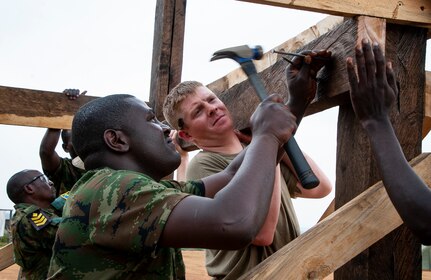 Members of the Rwanda Defense Force's Engineer Brigade work with Soldiers from the Nebraska Army National Guard's 623rd Engineer Company to build a guard tower, March 16, 2022, in Gako, Rwanda.