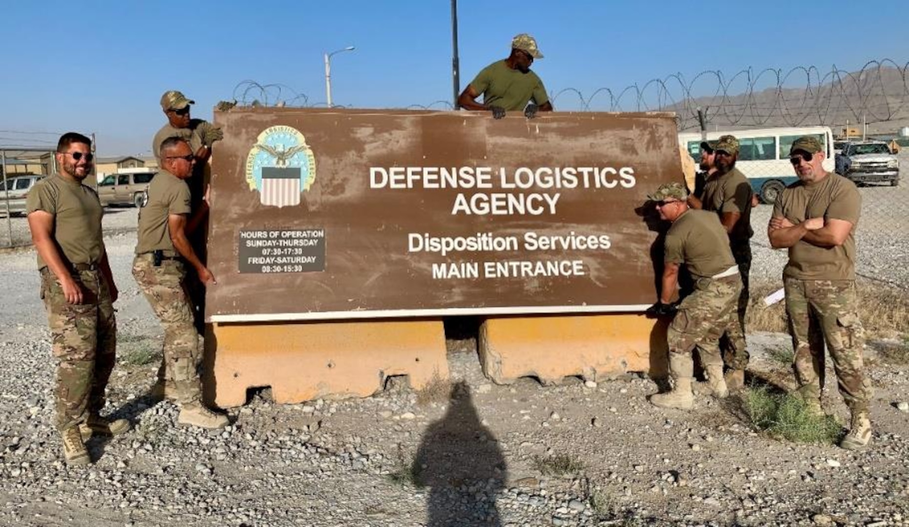 Disposition Services members next to DLA sign in Afghanistan