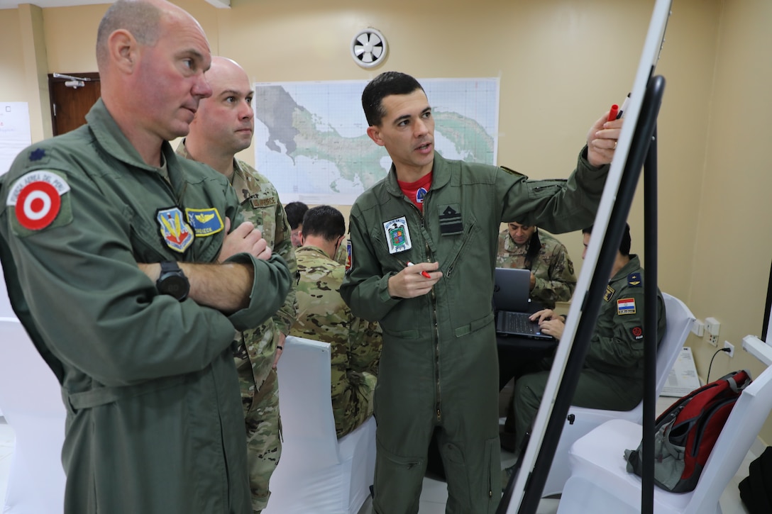 An Argentine military officer briefs a U.S. military and a Paraguayan military officer.