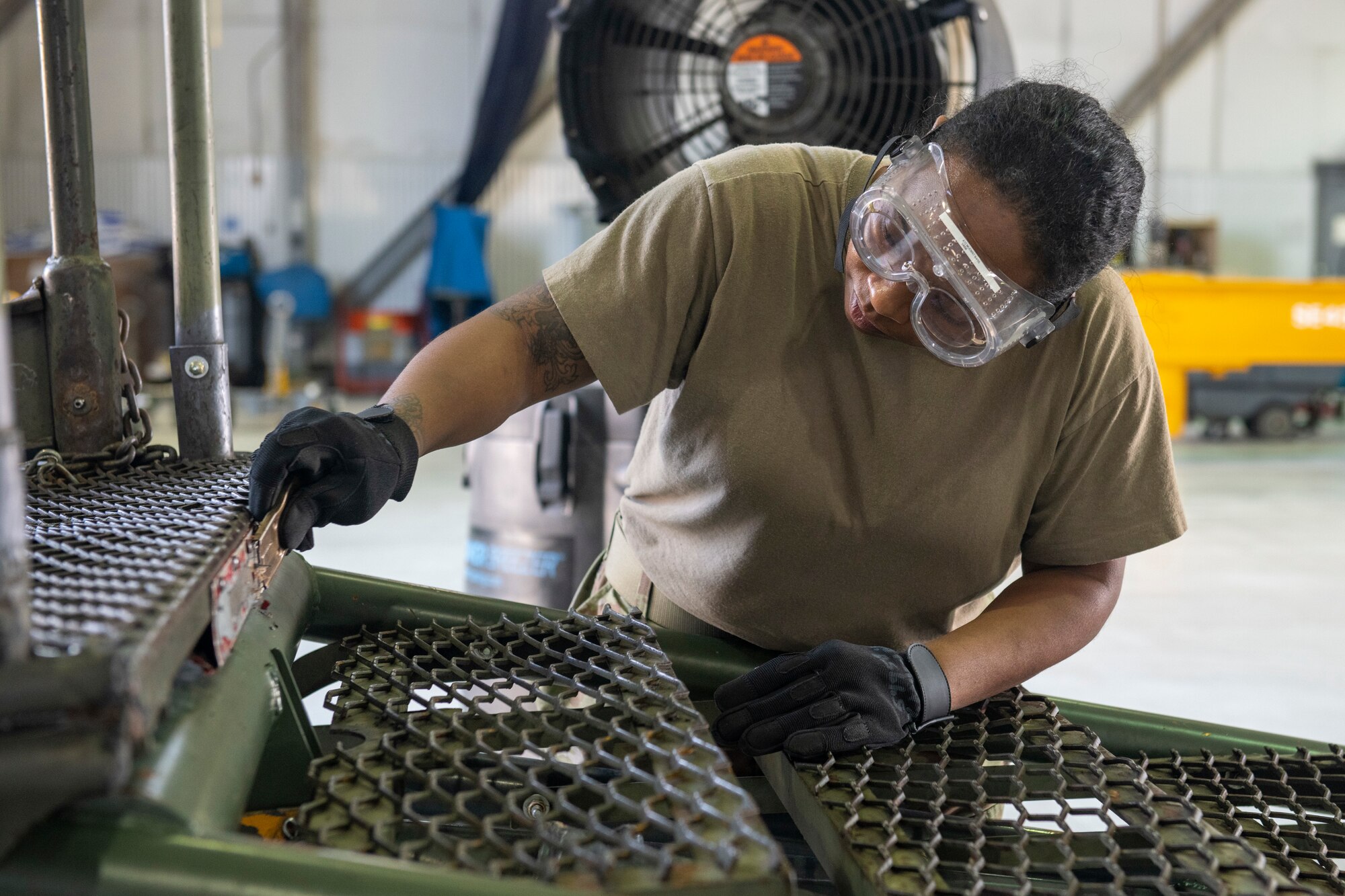 U.S. Air Force Senior Airman Naris Muenrit, 512th Maintenance Squadron aerospace ground equipment technician, scrapes old stenciling off of a B1 aircraft maintenance stand at Dover Air Force Base, Delaware, July 6, 2022. Over time, stencils fade and new ones must be re-adhered to provide warnings or directions for use of equipment. In keeping with their squadron’s motto, “Strength in Reserve,” Airmen at the 512th MXS routinely maintain ground equipment to be ready for use with any mission. (U.S. Air Force photo by Senior Airman Ruben Rios)