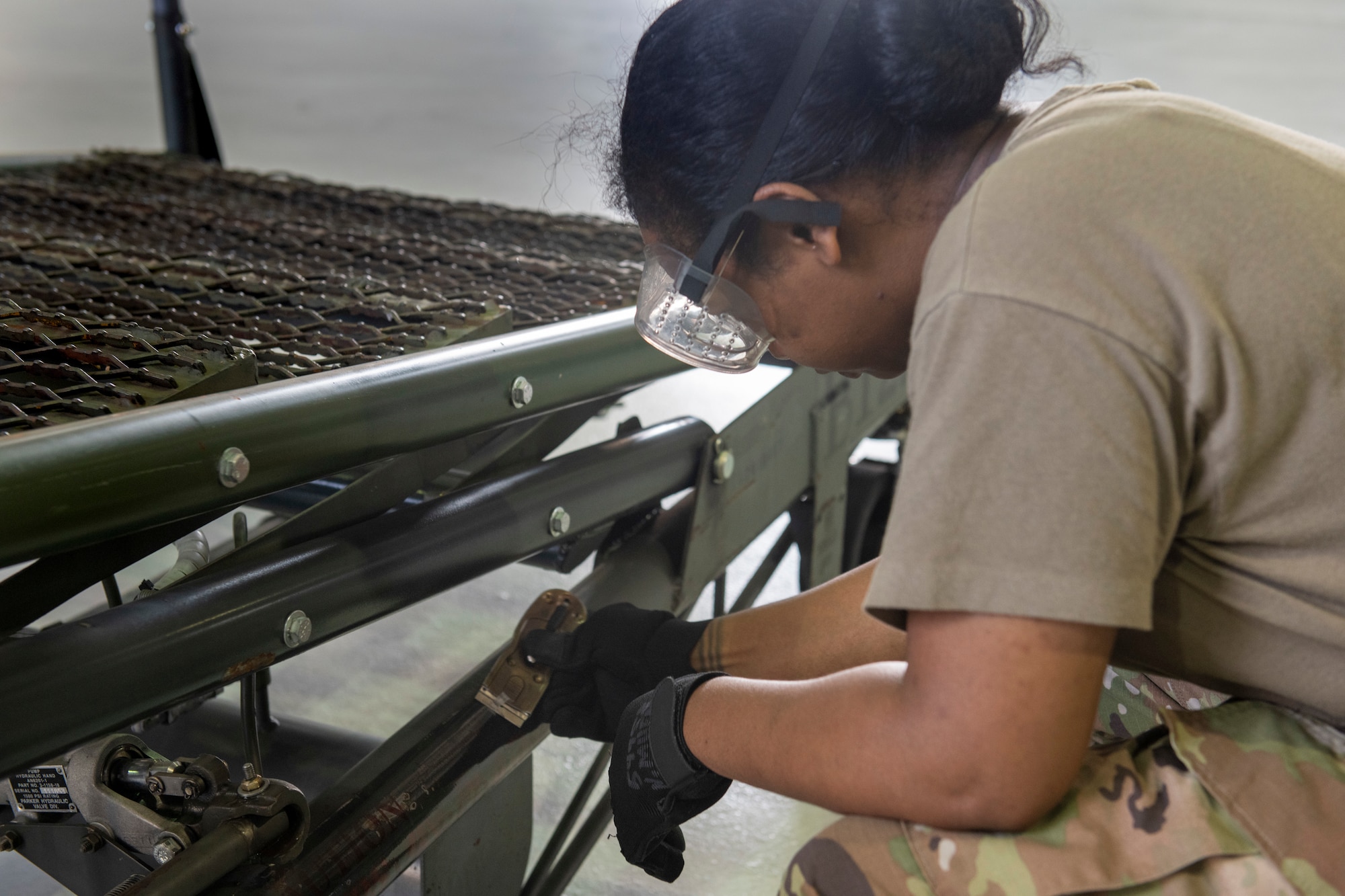 U.S. Air Force Senior Airman Naris Muenrit, 512th Maintenance Squadron aerospace ground equipment technician, scrapes old stenciling off of a B1 aircraft maintenance stand at Dover Air Force Base, Delaware, July 6, 2022. Over time, stencils fade and new ones must be re-adhered to provide warnings or directions for use of equipment. In keeping with their squadron’s motto, “Strength in Reserve,” Airmen at the 512th MXS routinely maintain ground equipment to be ready for use with any mission. (U.S. Air Force photo by Senior Airman Ruben Rios)