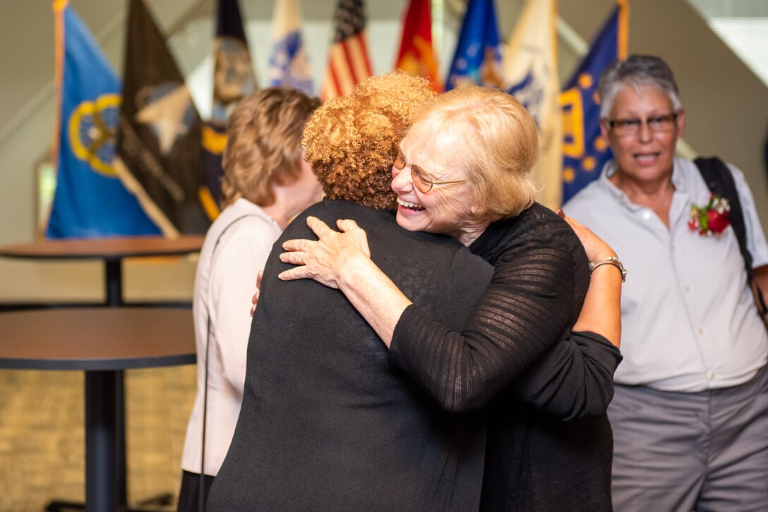 Two women hug in a room prior to the ceremony.