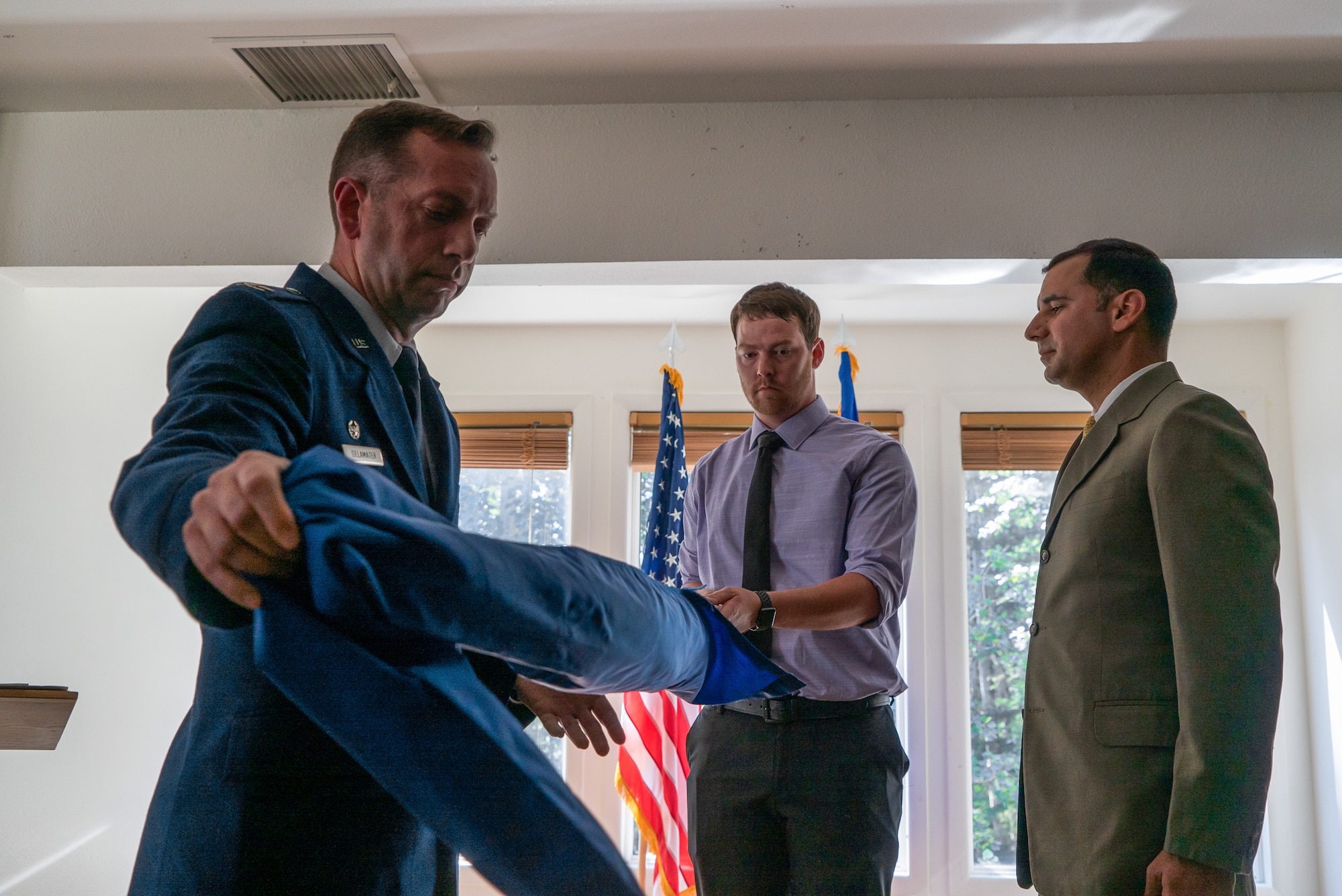 U.S. Air Force Col. Jason Delamater uncases a guidon with Curtis Benton and Joseph Dyson