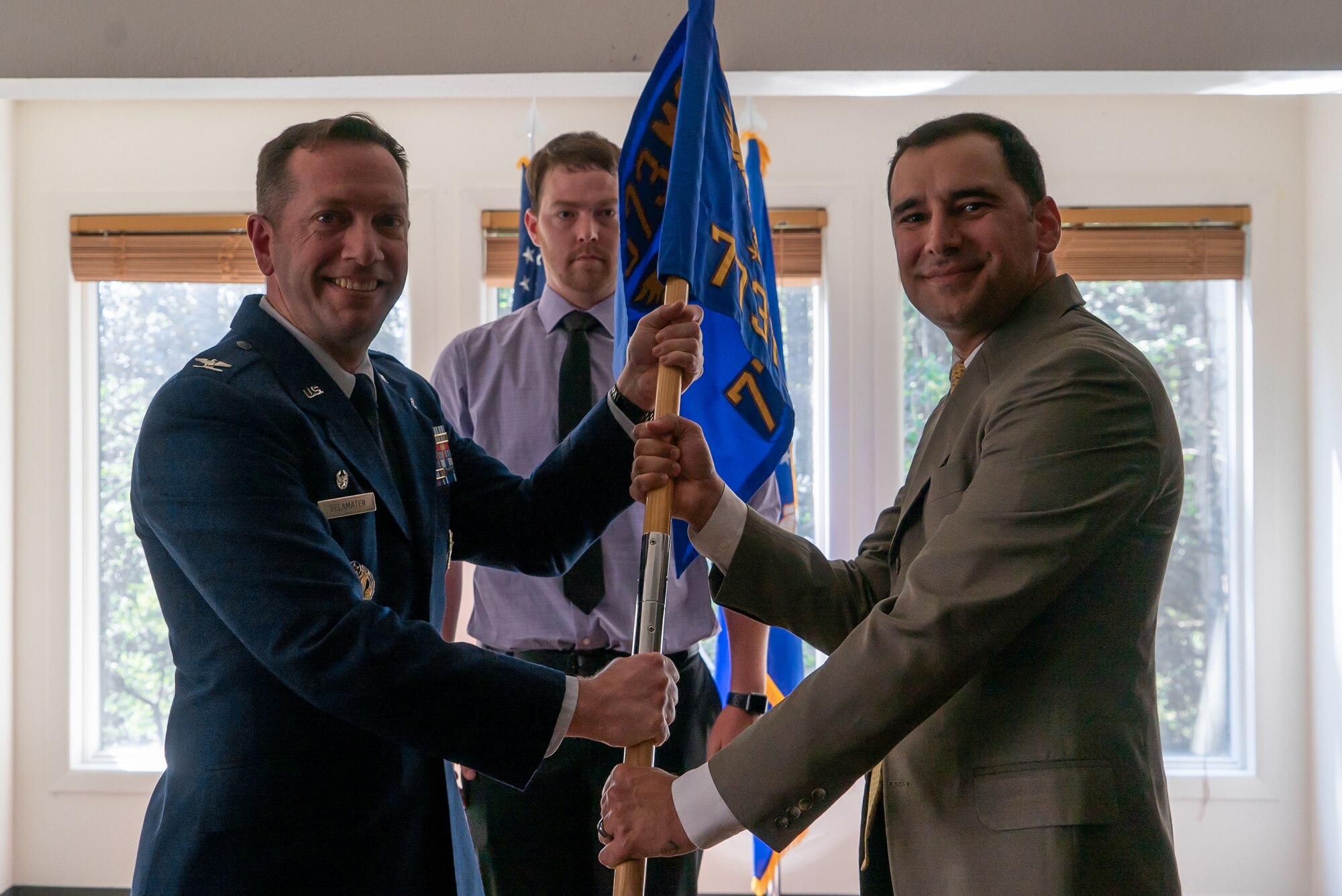 U.S. Air Force Col. Jason Delamater passes a guidon to Joseph Dyson