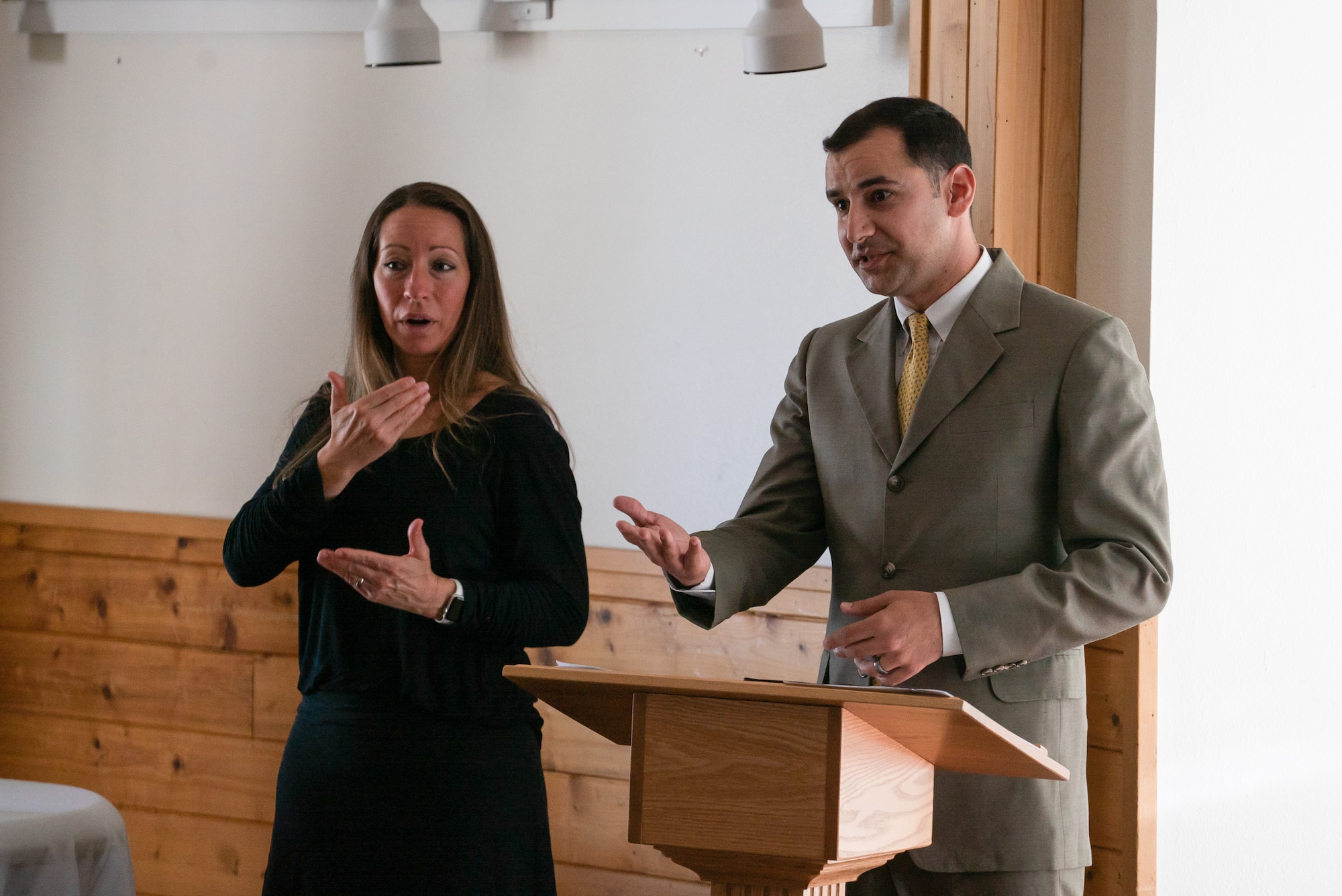 Joseph Dyson speaks at a podium while Liz Davidson interprets his words in sign language