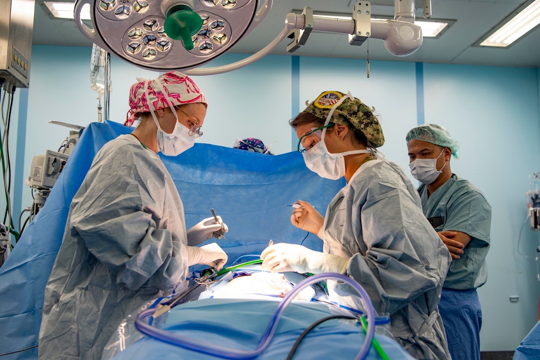 Two sailors perform surgery.