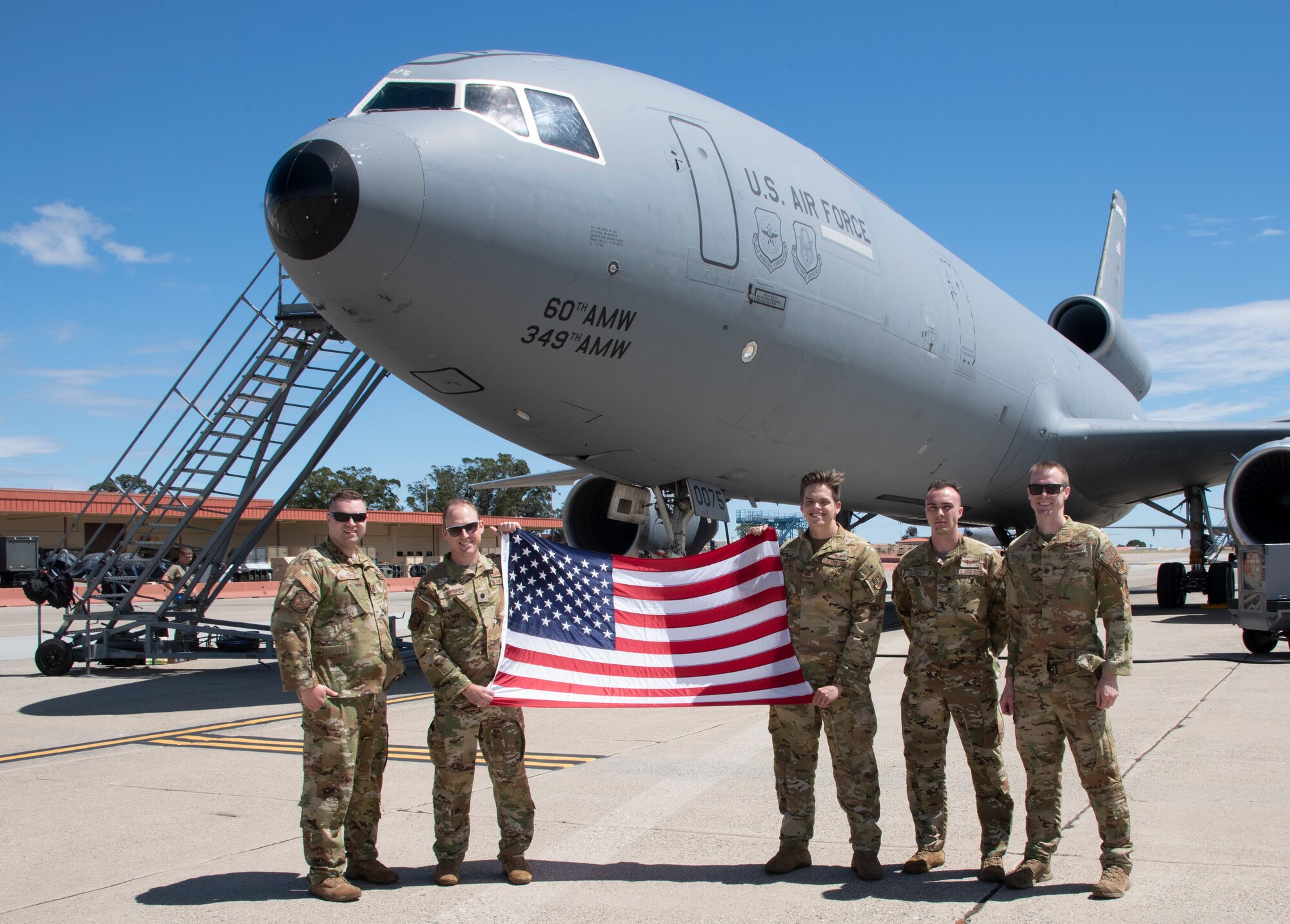 Airmen display the American flag in front of a KC-10 Extender.