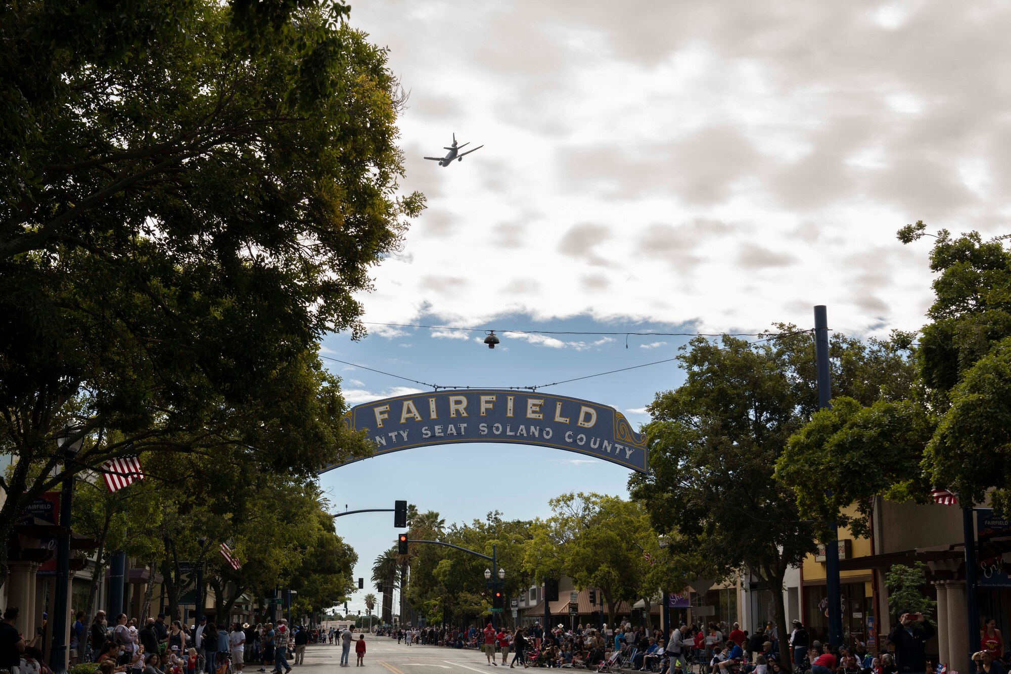 A plane flies over a town during a parade