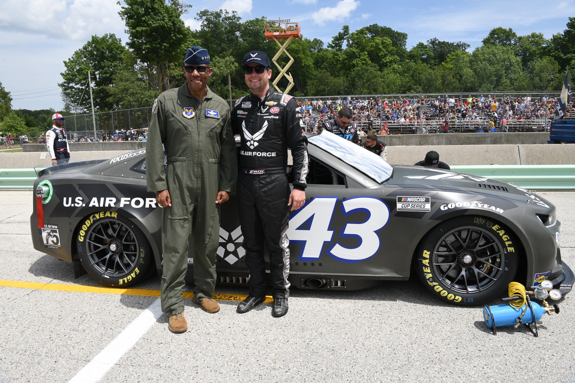 Air Force Chief of Staff Gen. CQ Brown, Jr., (left) posed for a photo in front of the Air Force-sponsored Chevrolet Camaro with driver Erik Jones of Petty GMS Motorsports near the Kwik Trip 250 NASCAR Cup Series finish line on the Road America course near Elkhart Lake, Wisconsin, July 3, 2022.