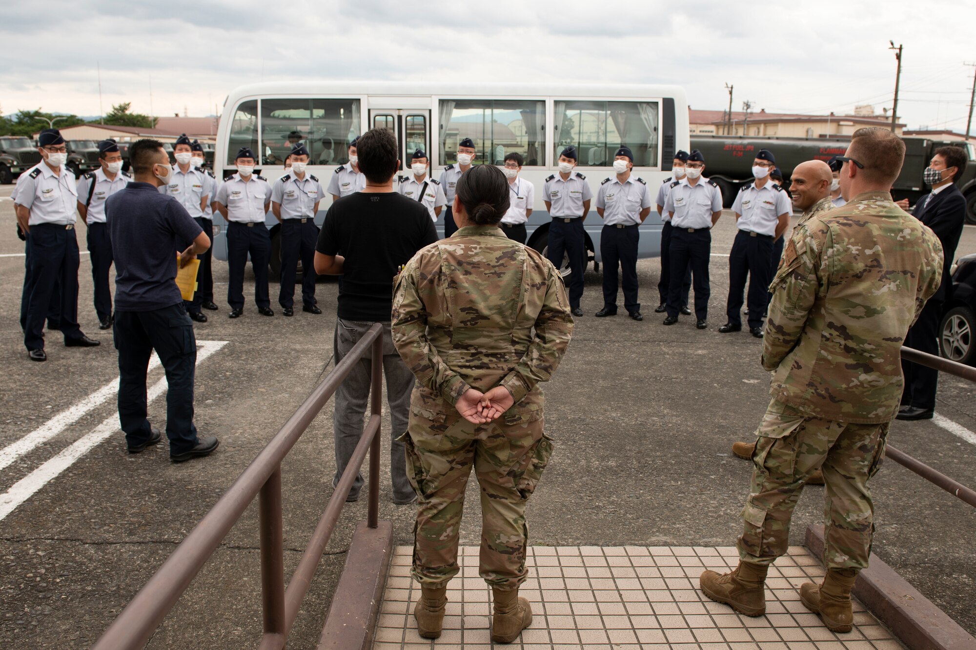 A group of multinational air force members stand in front of a bus