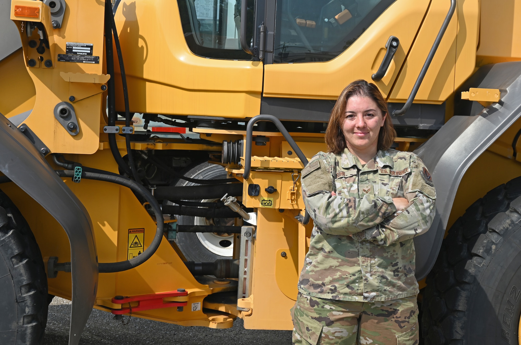 U.S. Air Force Senior Airman Alicia Buhr, a structures journeyman assigned to the 175th Civil Engineer Squadron, Maryland Air National Guard, poses for a photograph next to a loader at Warfield Air National Guard Base at Martin State Airport in Middle River, Maryland, June 5, 2022.