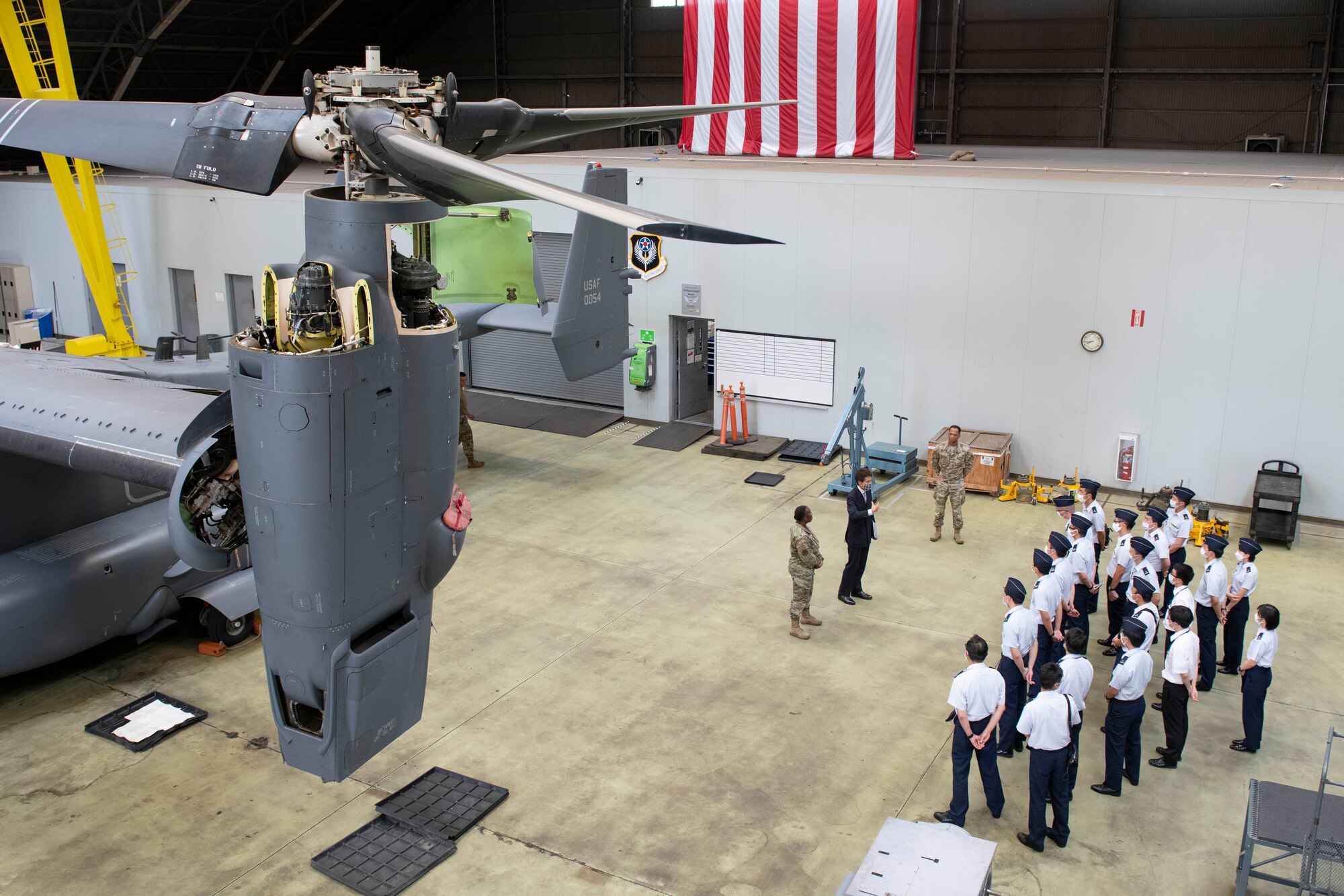Top down view of 18 Japanese air force cadets next to a helicopter