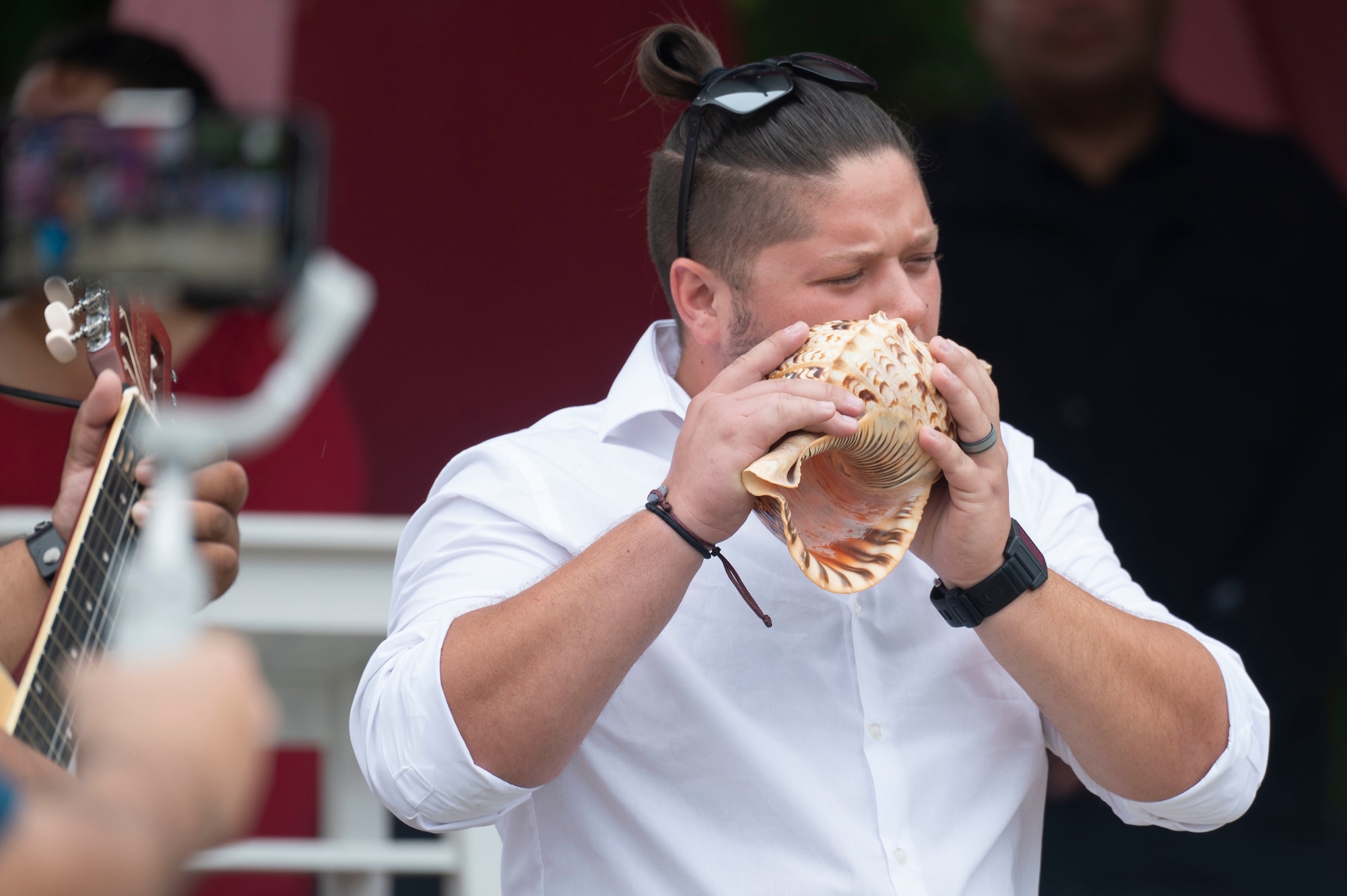 A man blows into a shell.