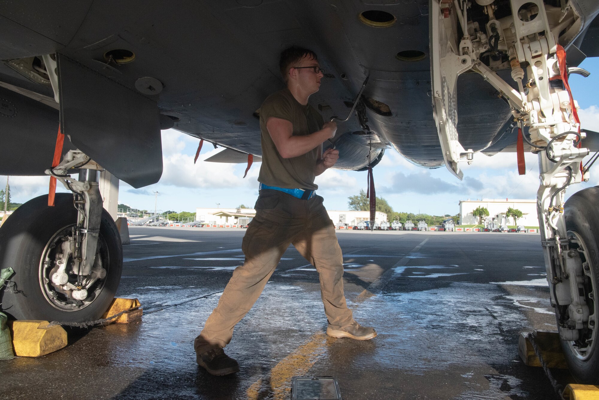 An Airman from the 44th AMU loosens screws from a panel on the underside of an F-15C Eagle.