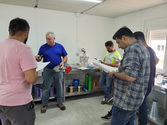 U.S. Army Corps of Engineers, Savannah District’s Mike Wielputz shows contractors how to conduct an Atterberg liquid limits test, which assesses the water contents which define the limits of various stages of consistency for fine-grained soils, as part of providing training on materials laboratory testing standards and necessary certifications in Powidz, Poland as part of the munitions storage area construction efforts June 29, 2022. The U.S. Army Corps of Engineers, Europe District construction involves building more than 50 bunkers, using roughly 17,500 cubic meters of concrete and the training is part of ensuring the project and its on-site concrete laboratory meet all required standards. (U.S. Army photo by Chad Gartrell)