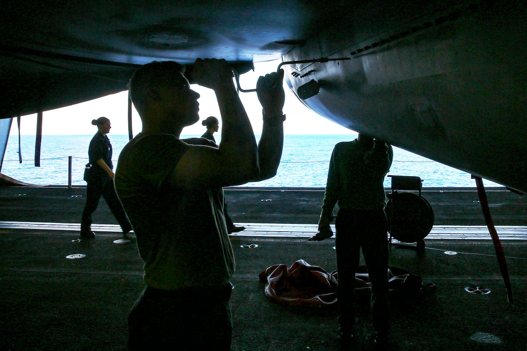 A sailor works on a military jet.