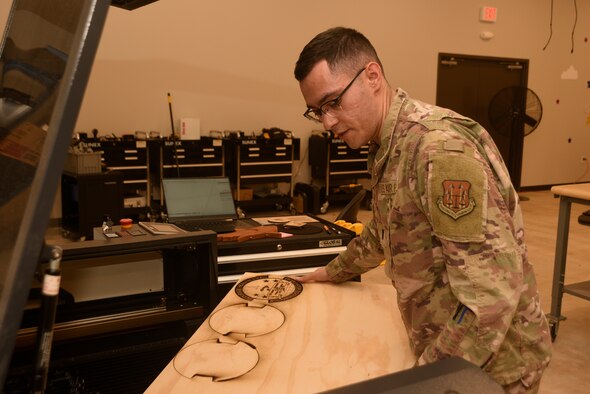 U.S. Air Force 1st Lt. Kennith McLoud, Air Force Operations Test and Evaluations Center operations research analyst, Eglin Air Force Base, Fla., places a piece of wood inside a laser engraver, June 29, 2022, at Patrick Space Force Base, Fla. McLoud is assisting Space Launch Delta 45’s innovation center, The Forge, develop solutions for more than a dozen issues at Patrick SFB and Cape Canaveral Space Force Station. (U.S. Space Force photo by Tech. Sgt. James Hodgman)