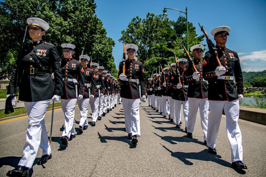 Marines walk in three lines down a road.