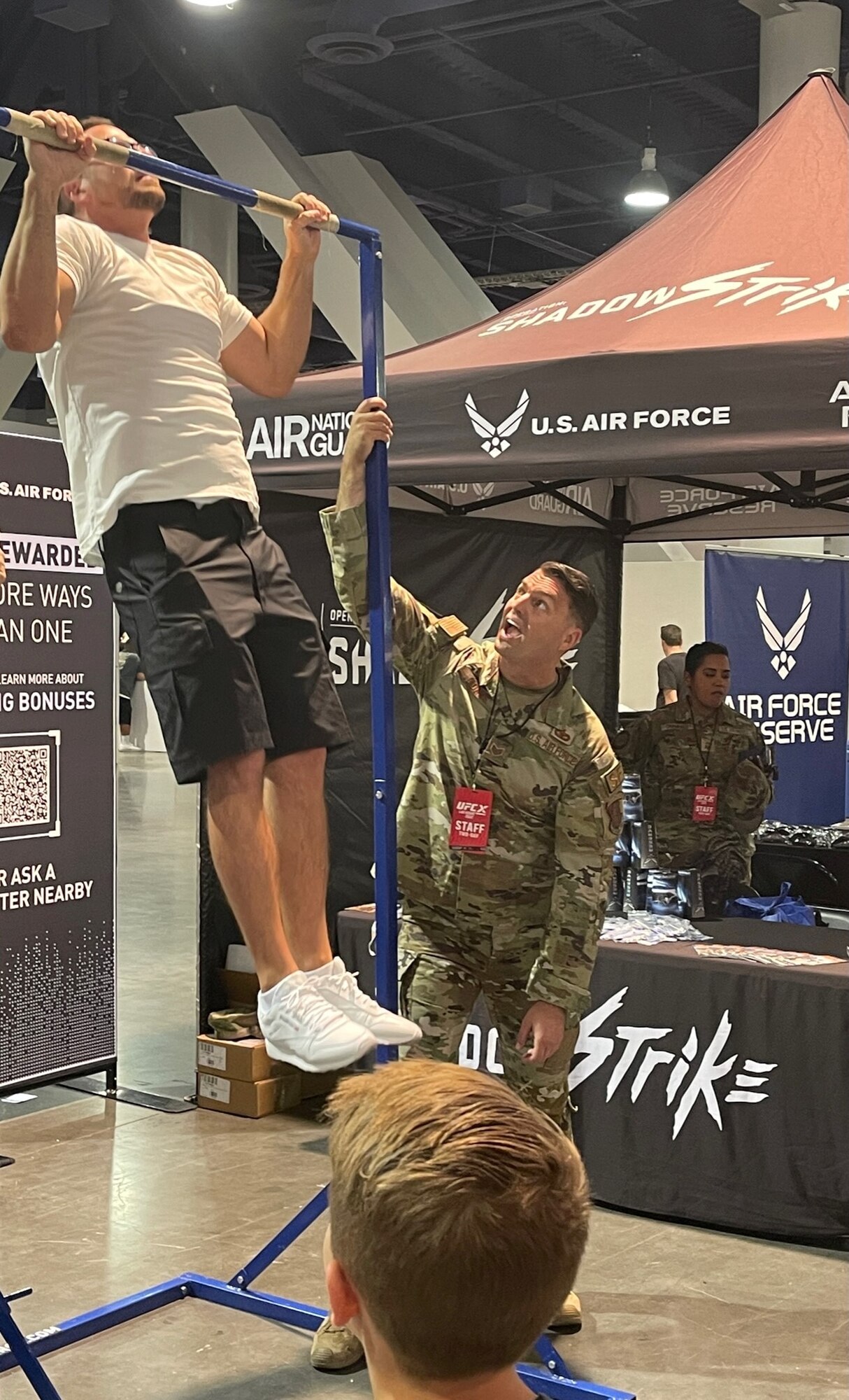 Staff Sgt. Chris Adams (right), a production recruiter for the Utah Air National Guard, encourages a participant on the pull up bars. Total Force recruiters from the ANG,