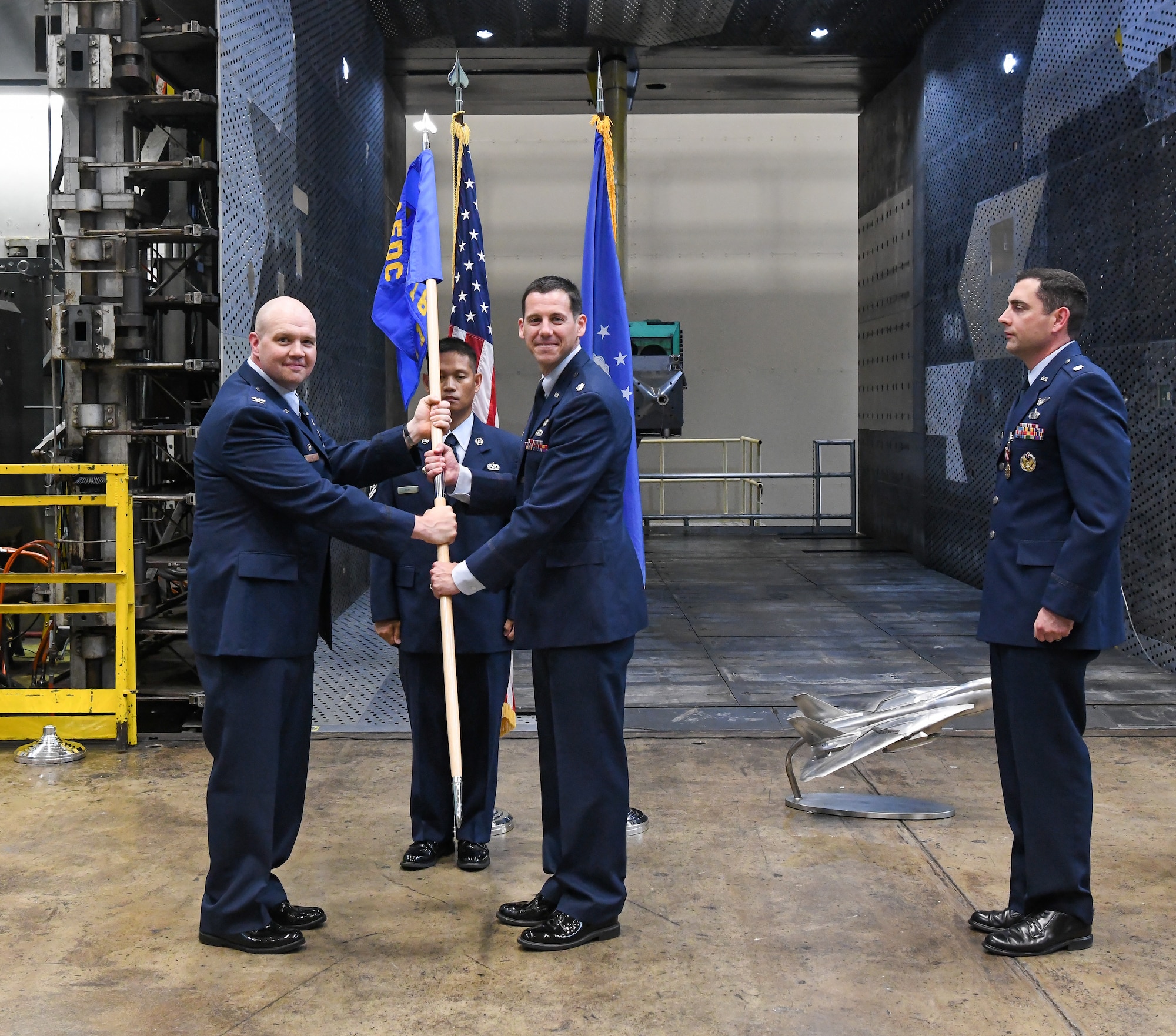 Col. Jason Vap, left, commander, 804th Test Group, passes the 716th Test Squadron guidon to Lt. Col. James Gresham charging him with command of the squadron during a change of command ceremony June 30, 2022.
