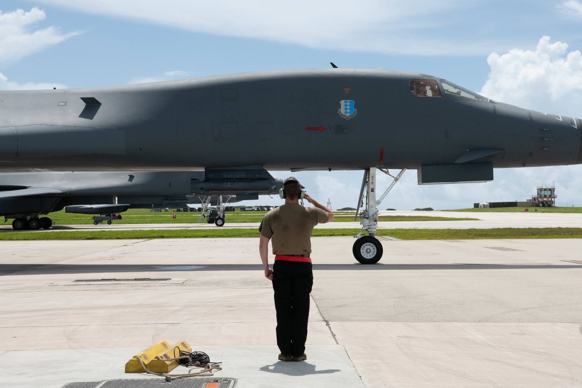 A U.S. Air Force service member, assigned to 34th Aircraft Maintenance Unit, salutes a B-1B Lancer taxing for takeoff at Andersen Air Force Base, Guam, for a Bomber Task Force mission, June 25, 2022.