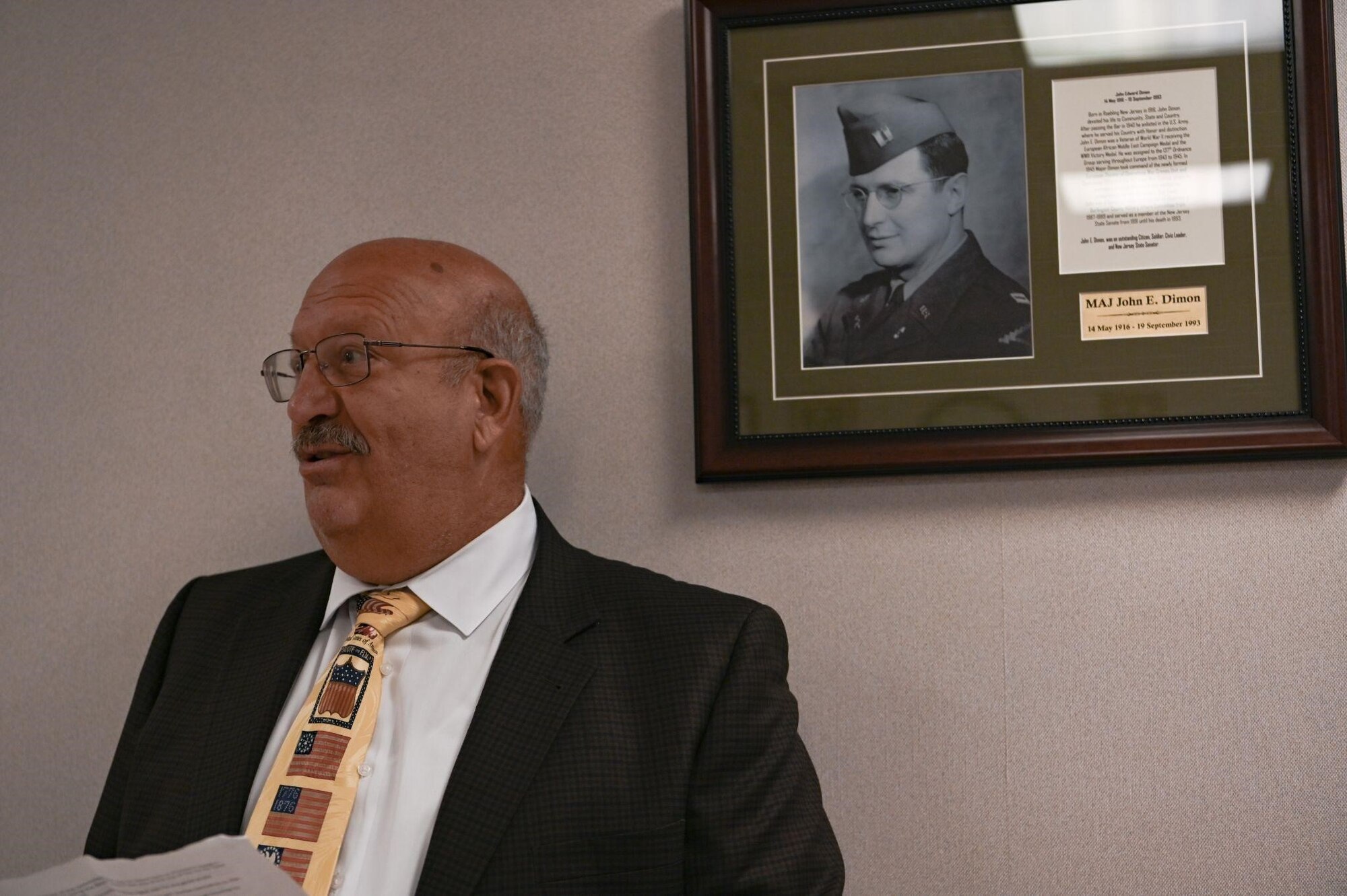 Man speaks in front of plaque