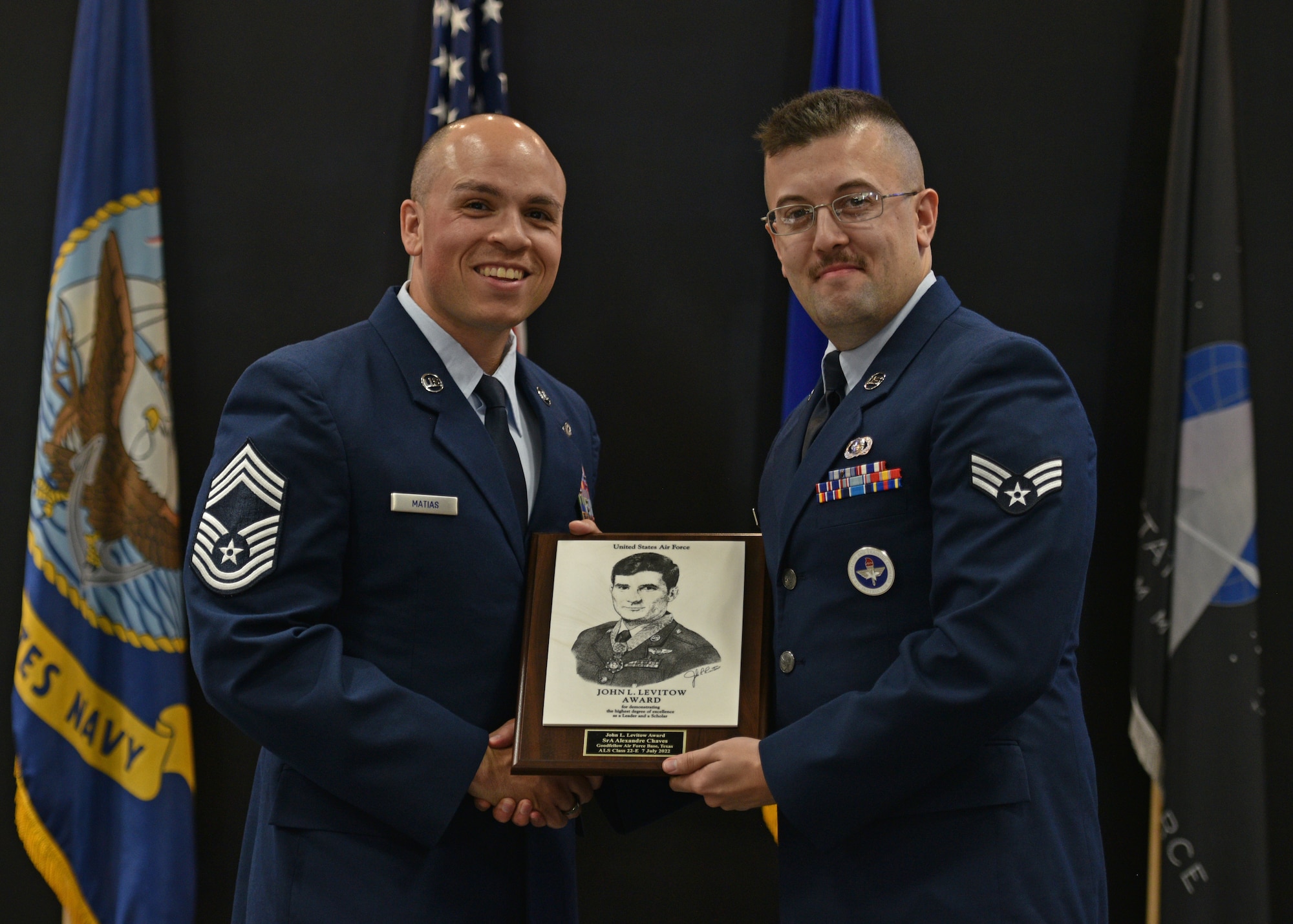U.S. Air Force Chief Master Sgt. Joshua Matias, 47th Operations Support Squadron senior enlisted leader, presents Senior Airman Alexandre Chaves, 315th Training Squadron instructor, with the John L. Levitow award during the Airman Leadership School graduation at the Powell Event Center, Goodfellow Air Force Base, Texas, July 7, 2022. The John L. Levitow award recognizes one student and is based upon all performance tasks, peer stratifications, and the capstone exercise. (U.S. Air Force photo by Senior Airman Ashley Thrash)