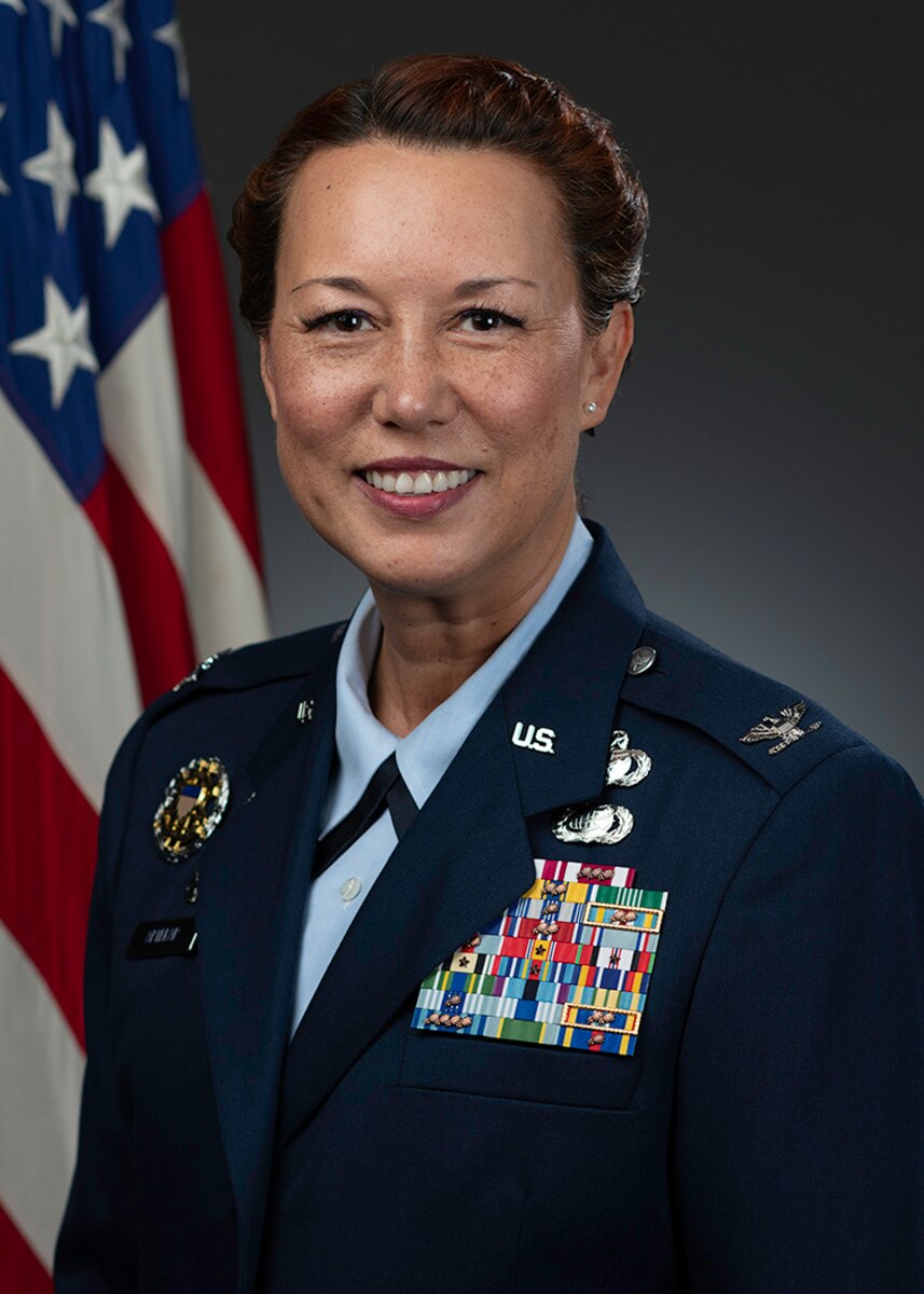 An Airman smiles for an official bio photo.