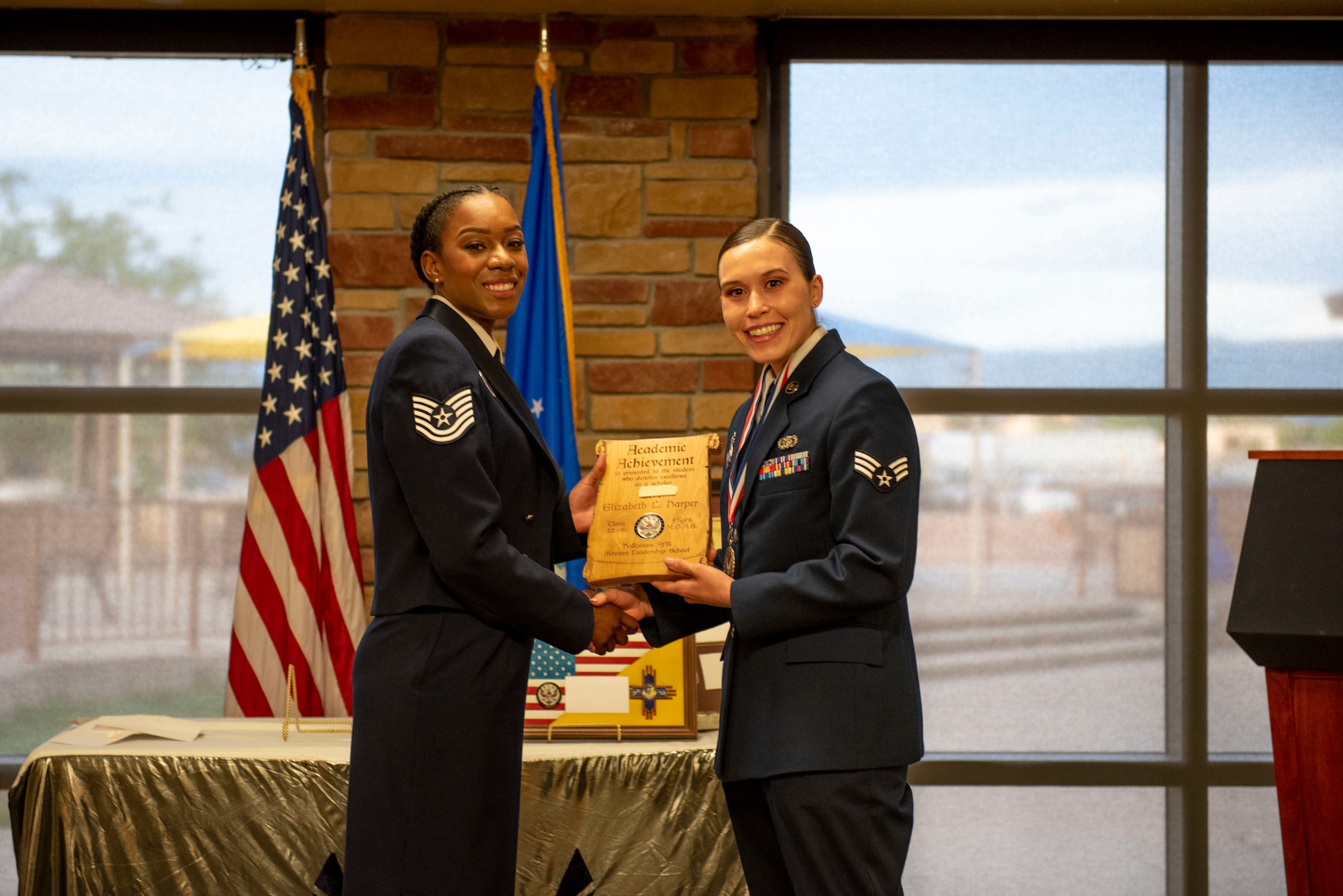 Senior Airman Elizabeth L. Harper, Airman Leadership School graduate, accepts the Academic Achievement Award from Tech Sgt. Shondra Nichols, 49th Force Support Squadron professional military education instructor, during the graduation of ALS class 22-6, July 7, 2022, on Holloman Air Force Base, New Mexico.