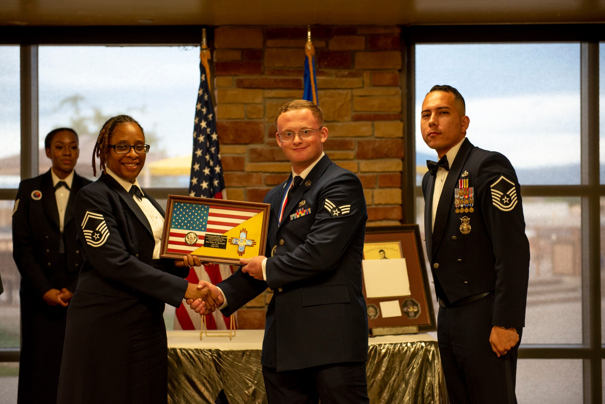 Senior Airman Silas Kornexl, Airman Leadership School graduate, middle, accepts the Commandant’s Award from Senior Master Sgt. Daisha Brown, 49th Logistics Readiness Squadron superintendent, left, and Master Sgt. Gabriel Larrazabal, 49th Force Support Squadron ALS Commandant, during the graduation of ALS class 22-6, July 7, 2022, on Holloman Air Force Base, New Mexico.