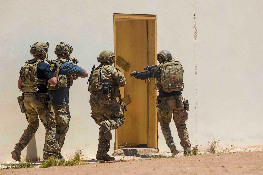 Four soldiers move toward an open door.