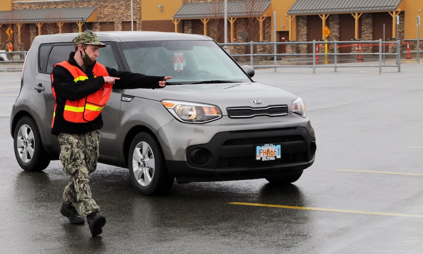Chief Quartermaster Michael Dixon, volunteer for the Alaska Naval Militia, assigned to Joint Task Force Alaska guides a local Alaskan into a parking lot at an expedient distribution center in Anchorage, Alaska, Apr. 20, 2020. Amidst the COVID-19 pandemic, Alaska National Guard Soldiers and members of the Alaska Organized Militia worked in a joint, logistical effort to assist the local food bank in feeding local Alaskans in need. (U.S. Army National Guard photo Sgt. Seth LaCount/Released)