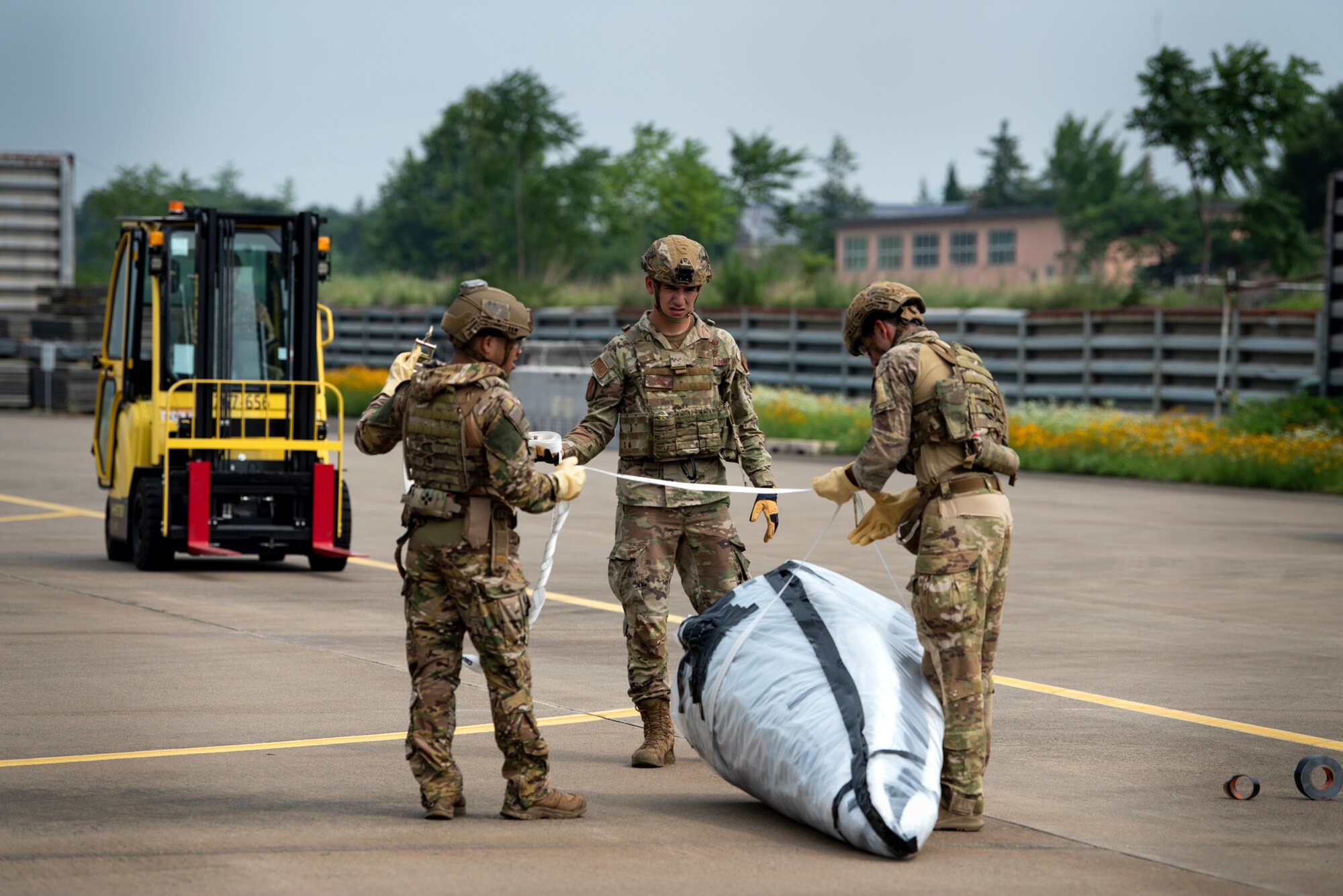 U.S. Air Force Senior Airmen Joshua Young and Omar Navarro, along with Staff Sgt. Michael Augustus, 35th Civil Engineer Squadron, Explosive Ordnance Disposal technicians from Misawa Air Base, Japan, prepare to transport a mock chemical weapon during a bilateral training scenario at Suwon Air Base, Republic of Korea, July 6, 2022.