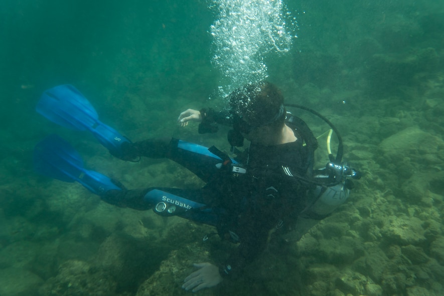 Diver sits underwater, air tank bubbles.