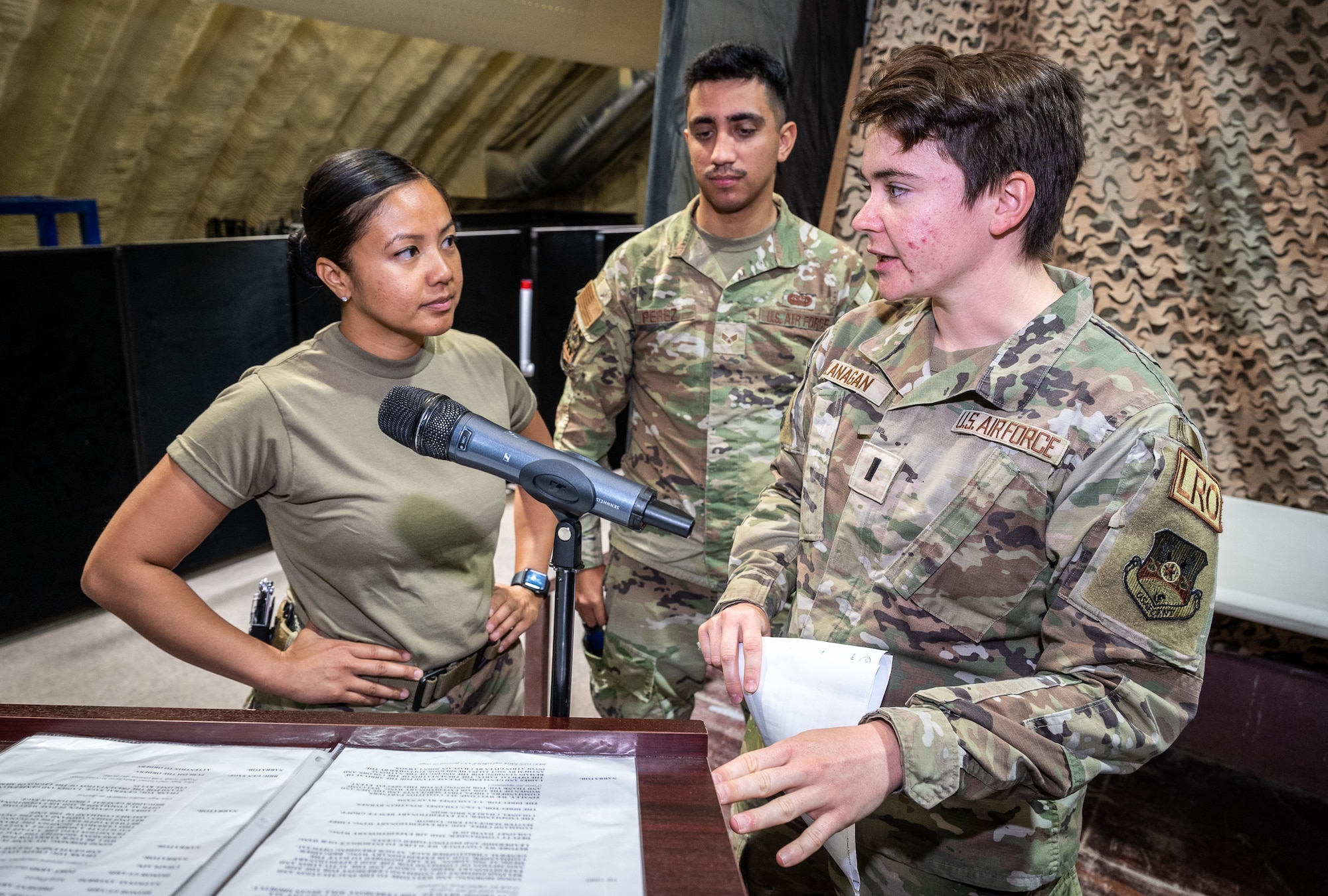 1st. Lieutenant Brittany Flanagan, 332d Air Expeditionary Wing protocol officer in charge, reviews the order of ceremony with Master Sgt. Julynn Gonzalez, 332d Expeditionary Medical Squadron medical operations flight chief and ceremony emcee, in preparation for the 332d Expeditionary Medical Squadron assumption of command ceremony at an undisclosed location in Southwest Asia, June 24, 2022.  (U.S. Air Force photo by Master Sgt. Christopher Parr)