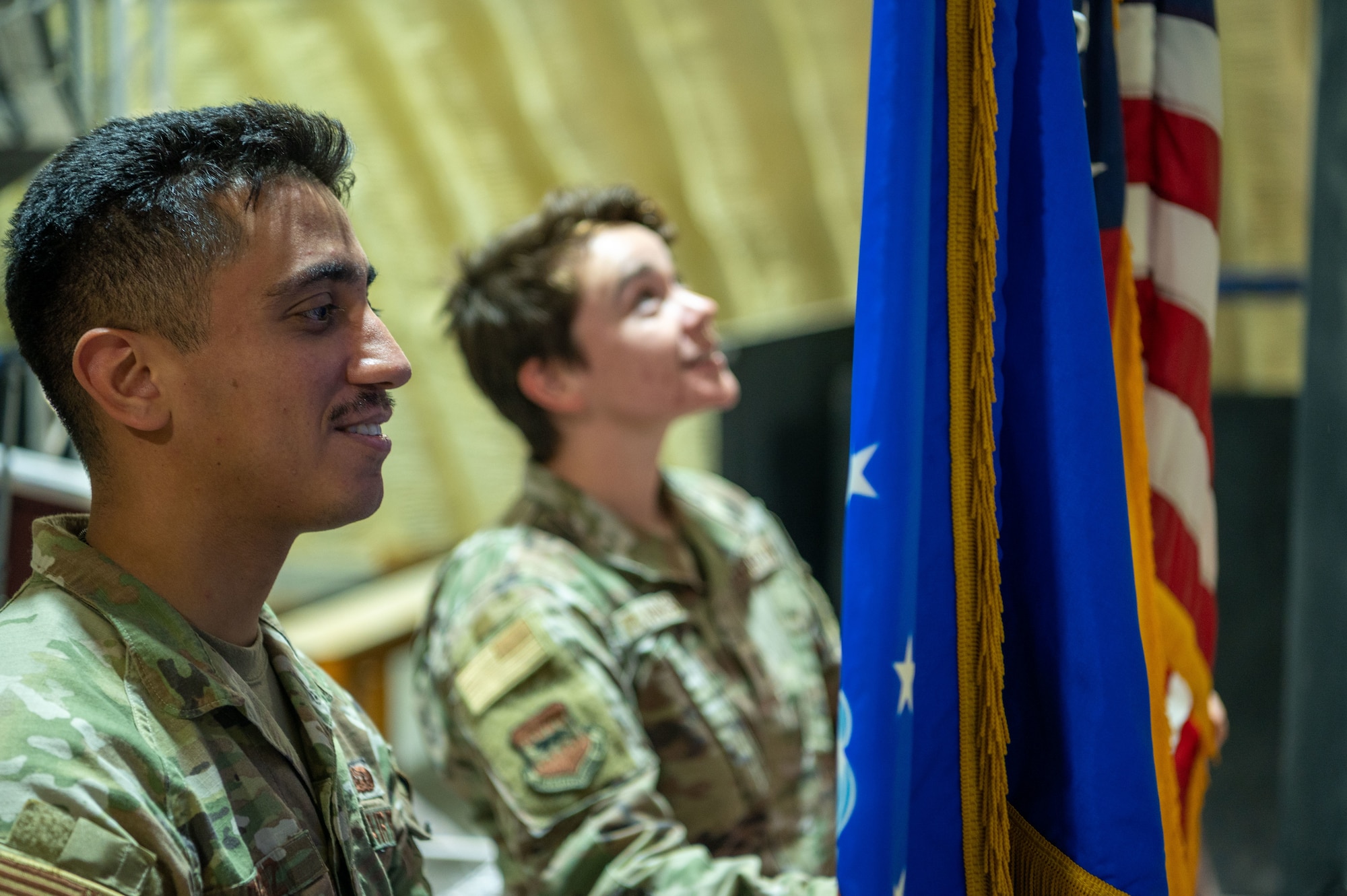 Senior Airman Isaac Perez, 332d Air Expeditionary Wing protocol specialist, and 1st. Lieutenant Brittany Flanagan, 332d AEW protocol officer in charge, display the U.S. Air Force and U.S. flags on stage in preparation for an official ceremony at an undisclosed location in Southwest Asia, June 27, 2022. The 332d AEW Protocol office manages official events and distinguished visitor engagements ensuring key leader engagements meet mission objectives and partner nation customs and courtesies are observed. (U.S. Air Force photo by Master Sgt. Kelly Goonan)