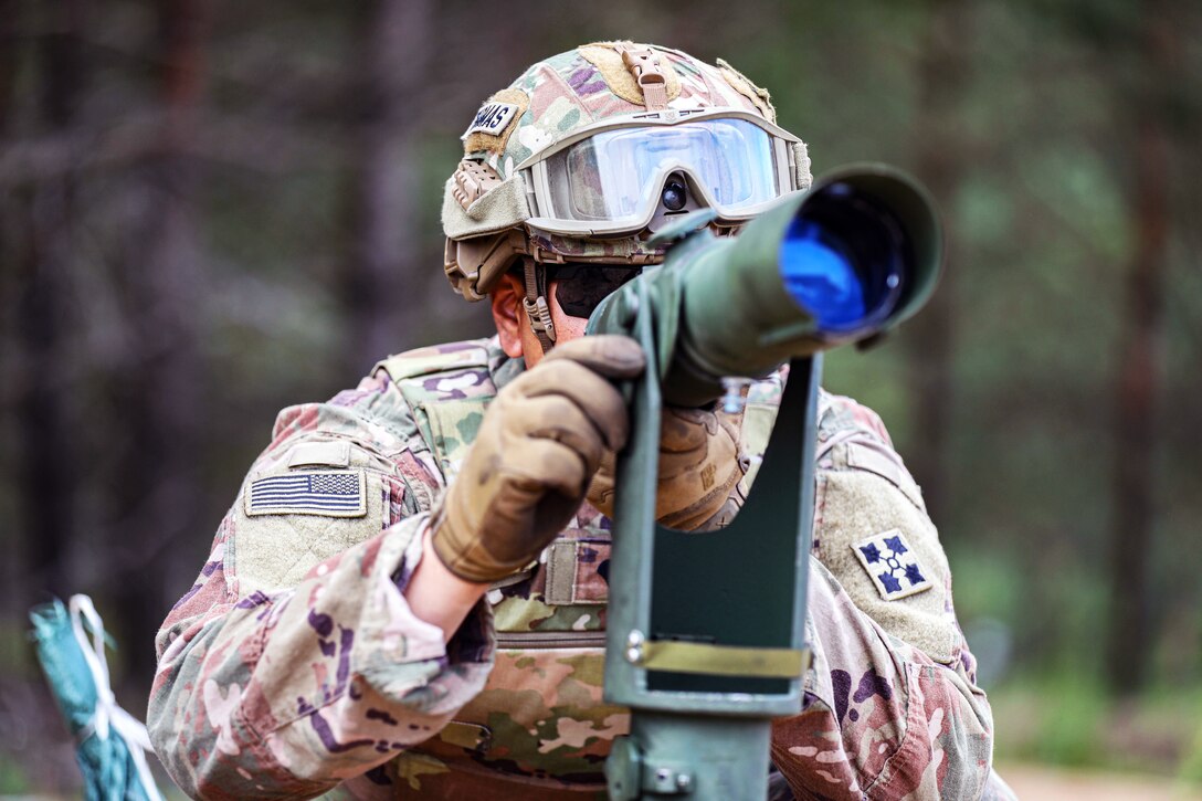 A soldier looks through a scope while performing qualification tasks for M109 Paladin howitzer crew.